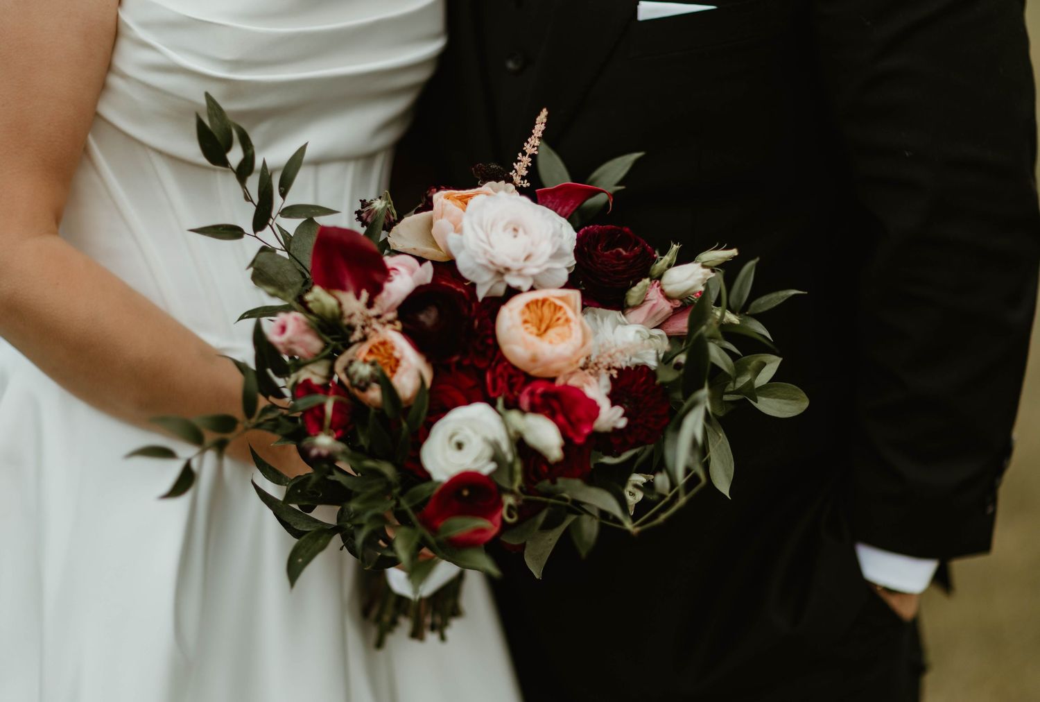 A stunning bridal bouquet featuring pink and burgundy flowers with green foliage.