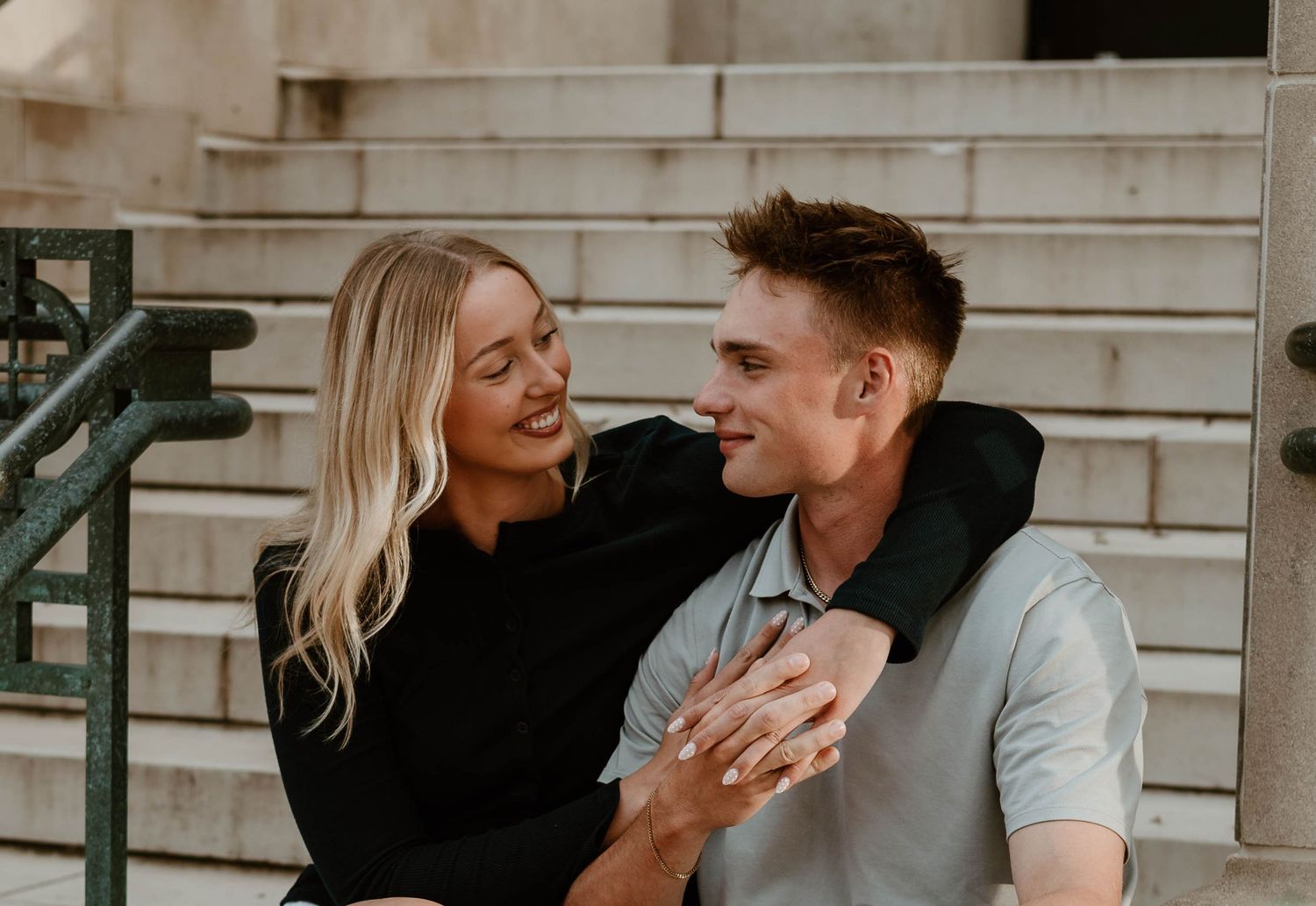 A couple shares a tender moment while sitting on outdoor steps during a warm sunset.