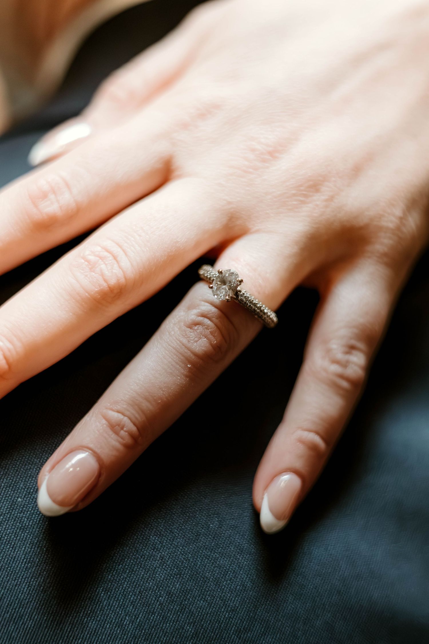 Close-up shots of an engagement ring on a woman's hand against a dark background.