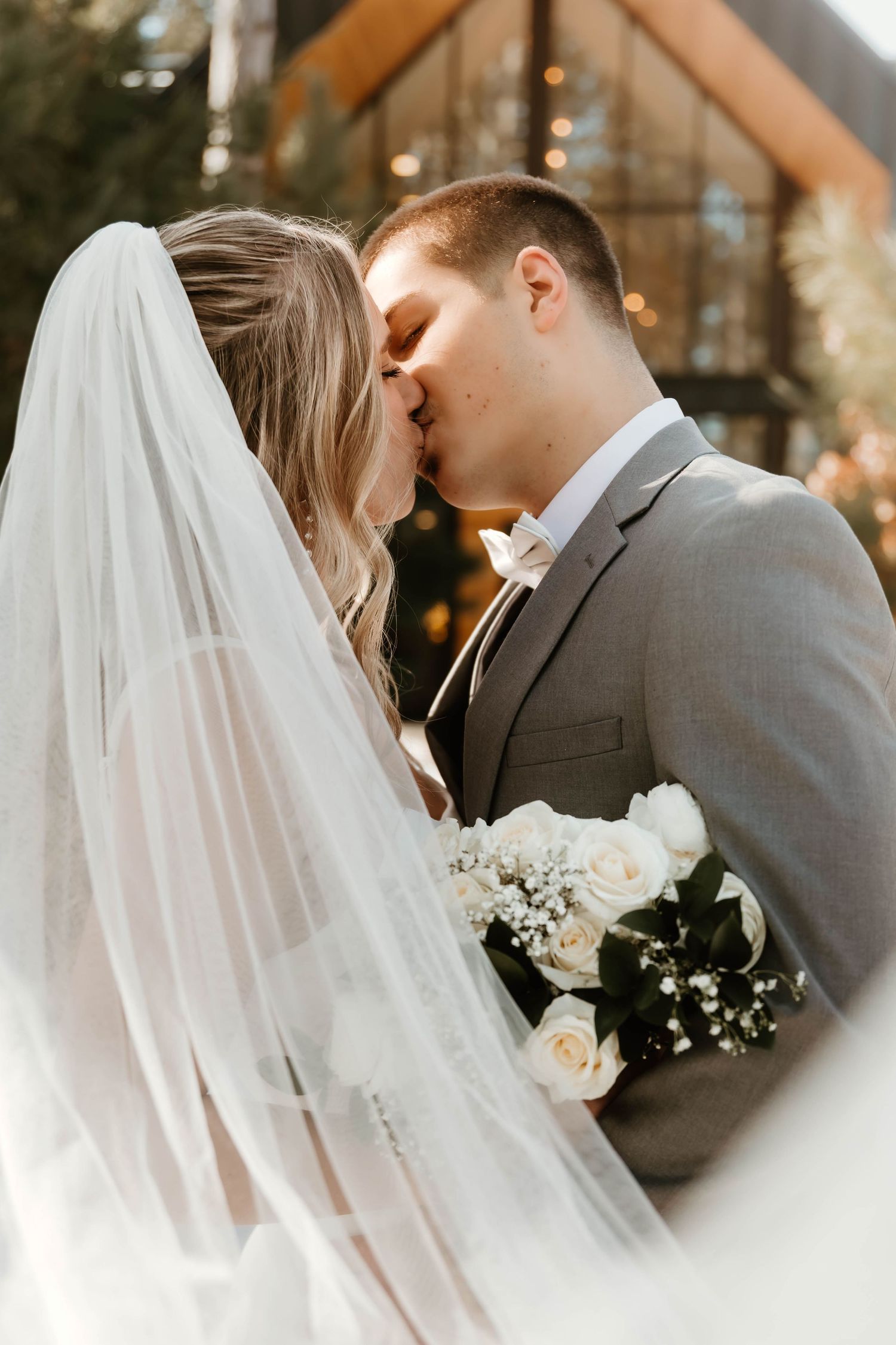 Romantic winter wedding portrait with flowing veil and white bouquet.
