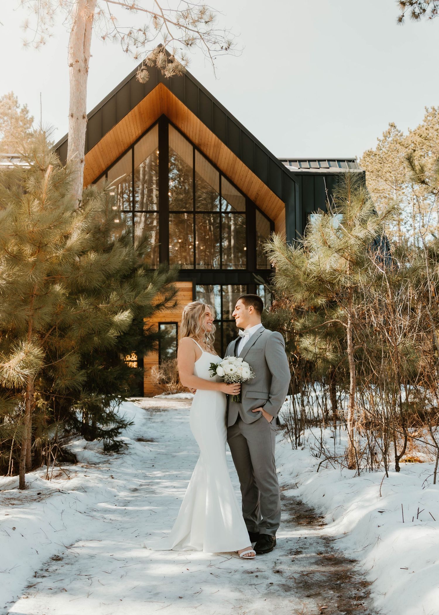 A snowy winter wedding photoshoot outside a modern A-frame chapel.
