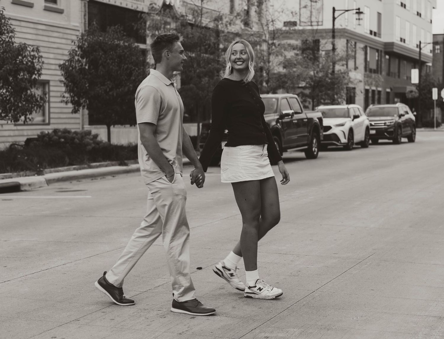 A black and white photo of two people walking together on a city street.