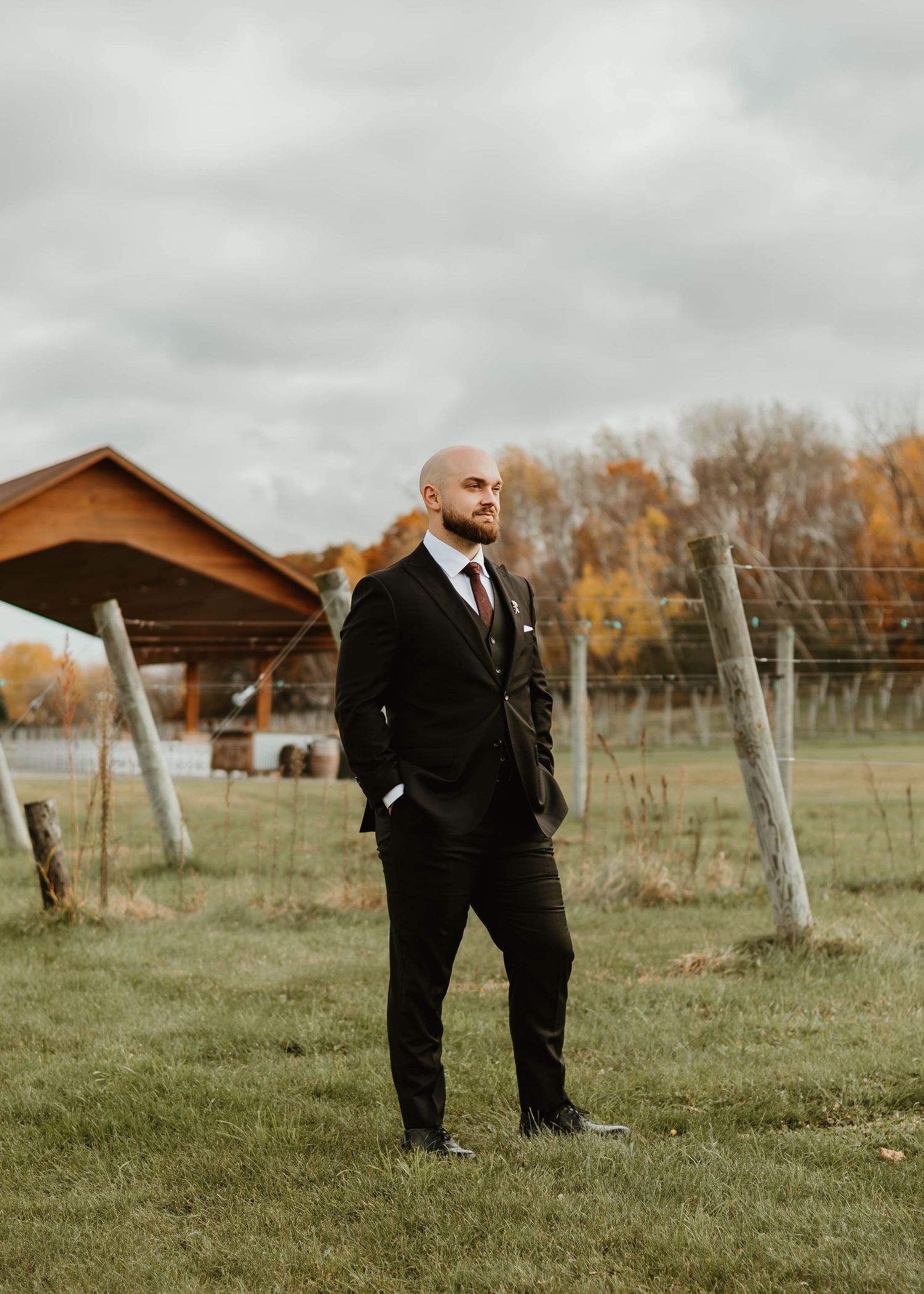 A couple shares a romantic moment in a vineyard during autumn with overcast skies.