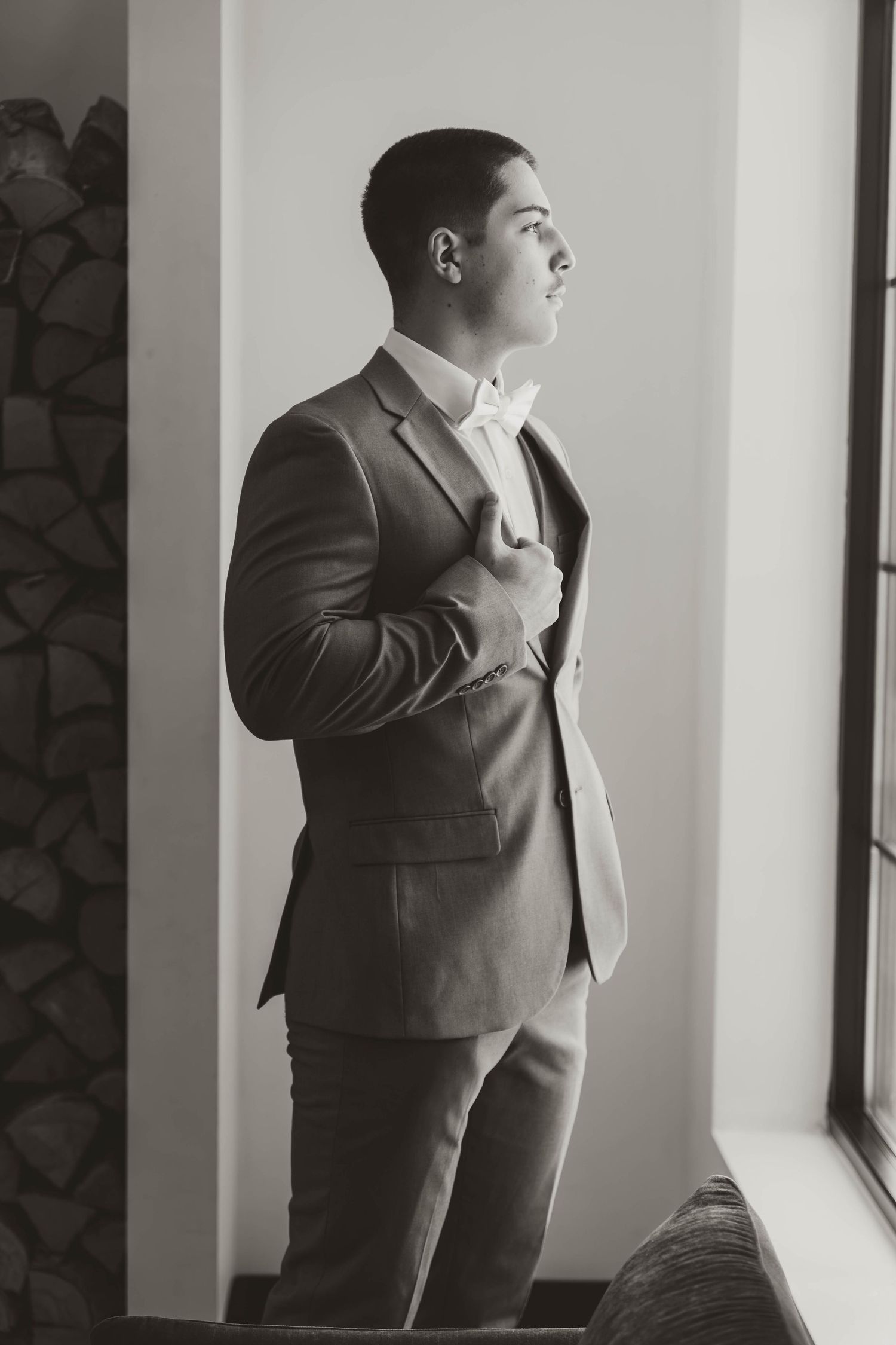 Person in a gray suit adjusting their tie while getting ready.
