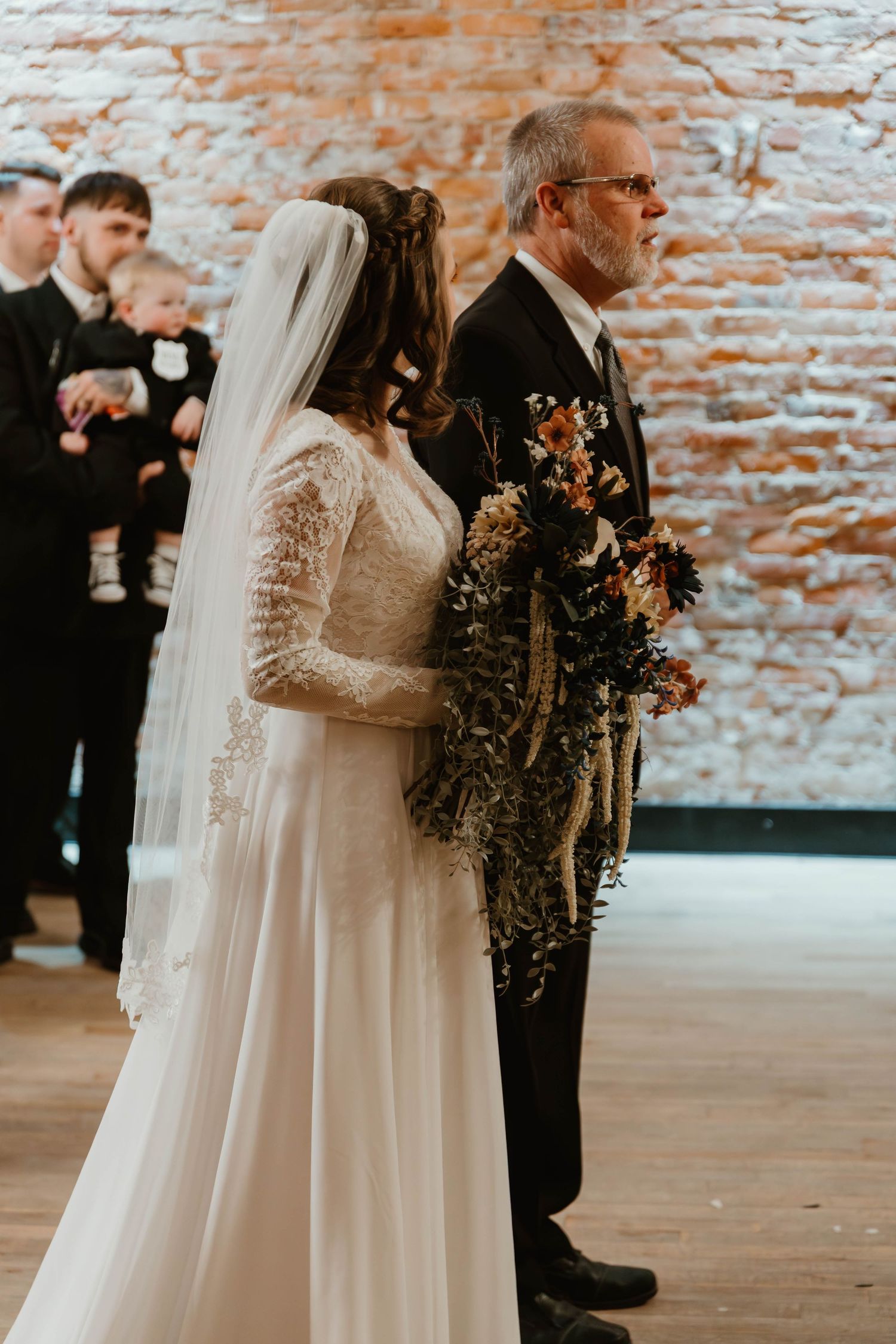 Wedding ceremony moment in industrial venue with exposed brick walls.