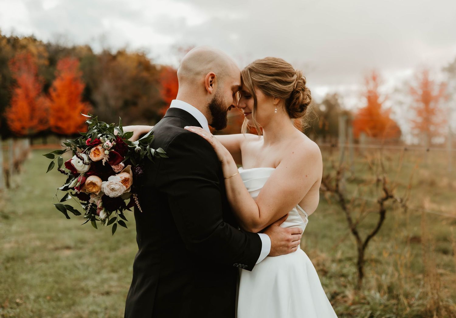 Romantic fall wedding portraits with autumn foliage and warm colors in the background.