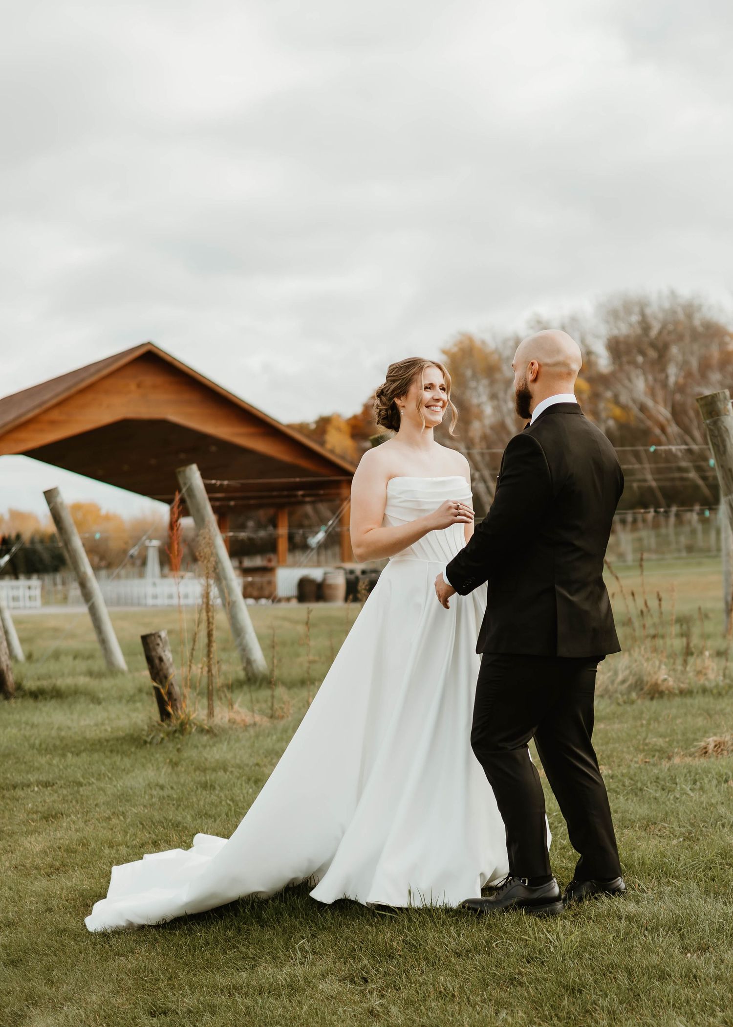 A couple shares an intimate dance together on a grassy field during an autumn wedding celebration.