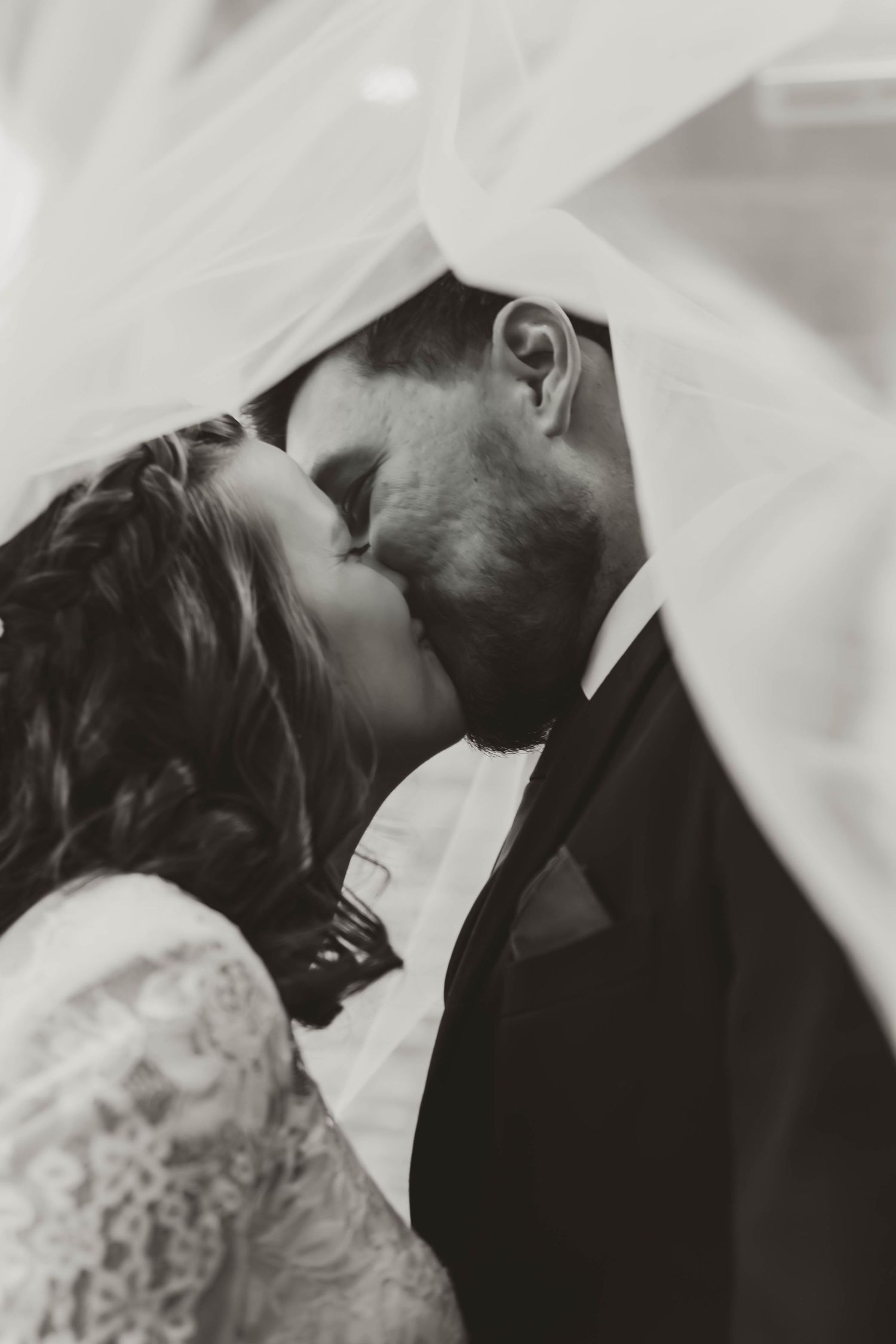 Intimate black and white wedding portrait under flowing veil.