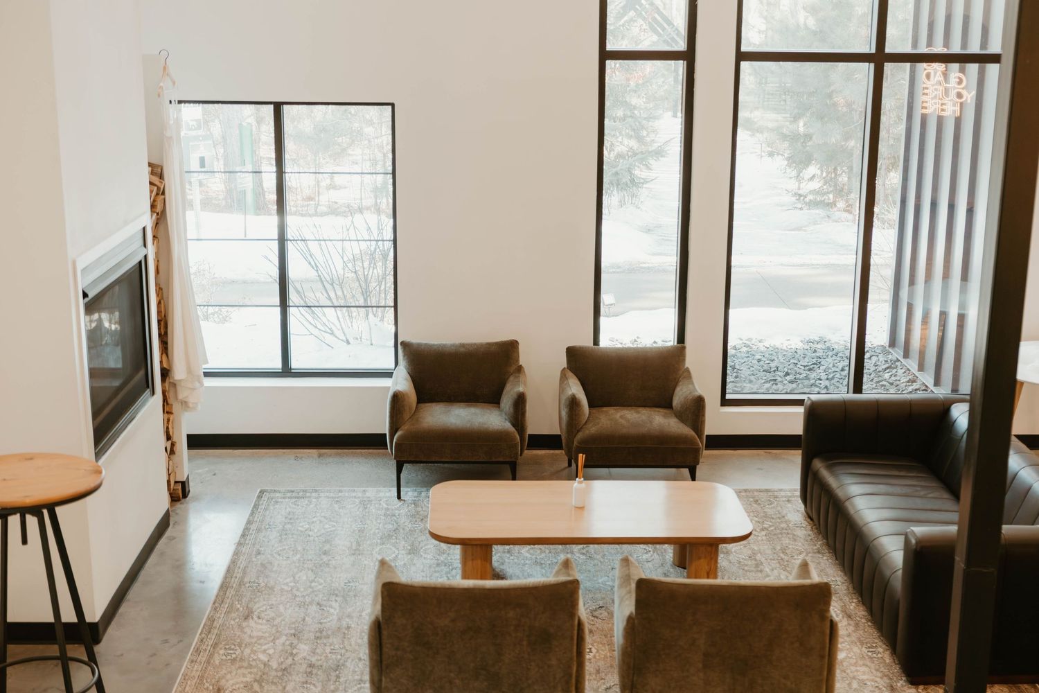 Modern interior with large windows, wooden furniture, and natural light flooding the space.