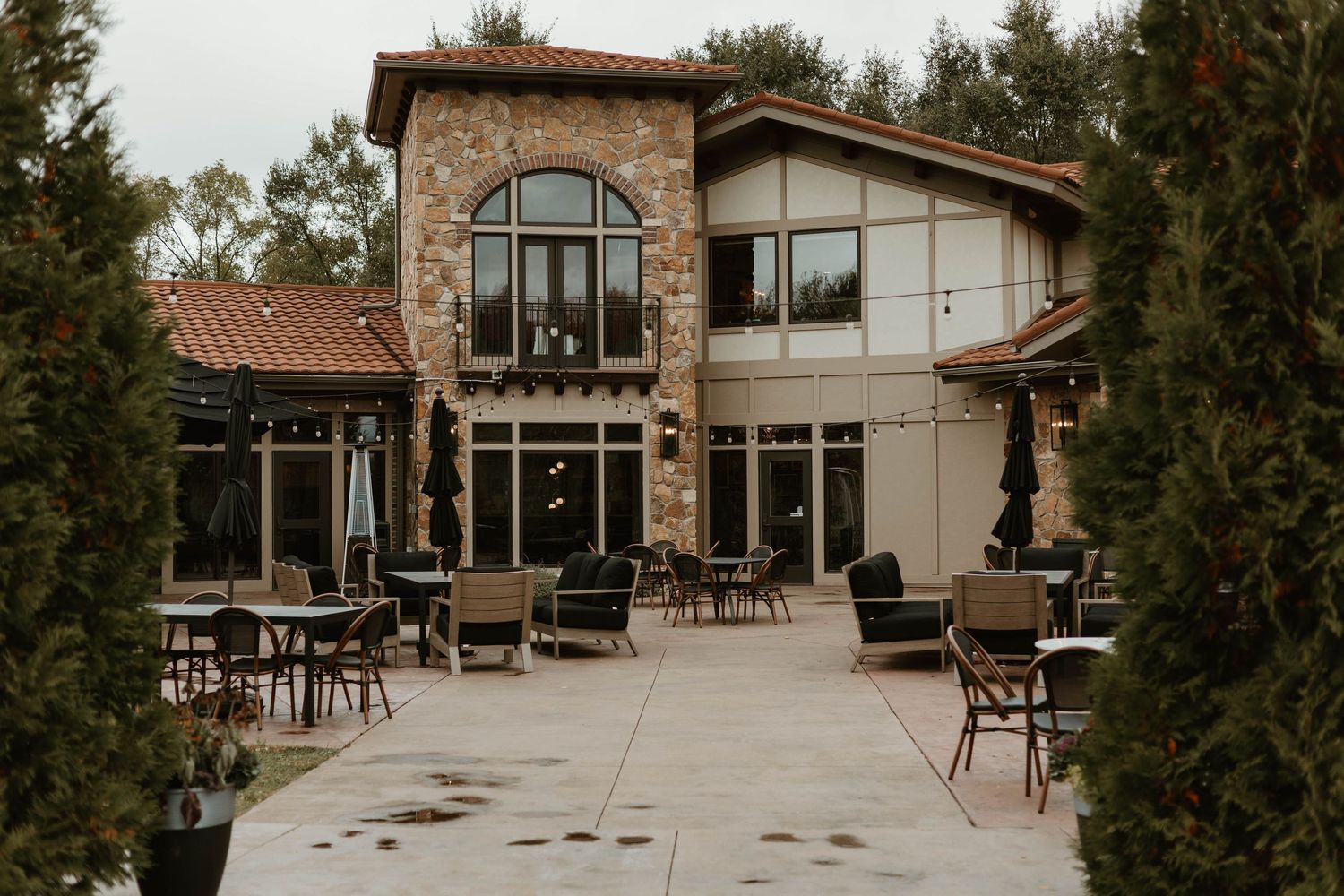 Stone and white building exterior with outdoor seating area and autumn trees.