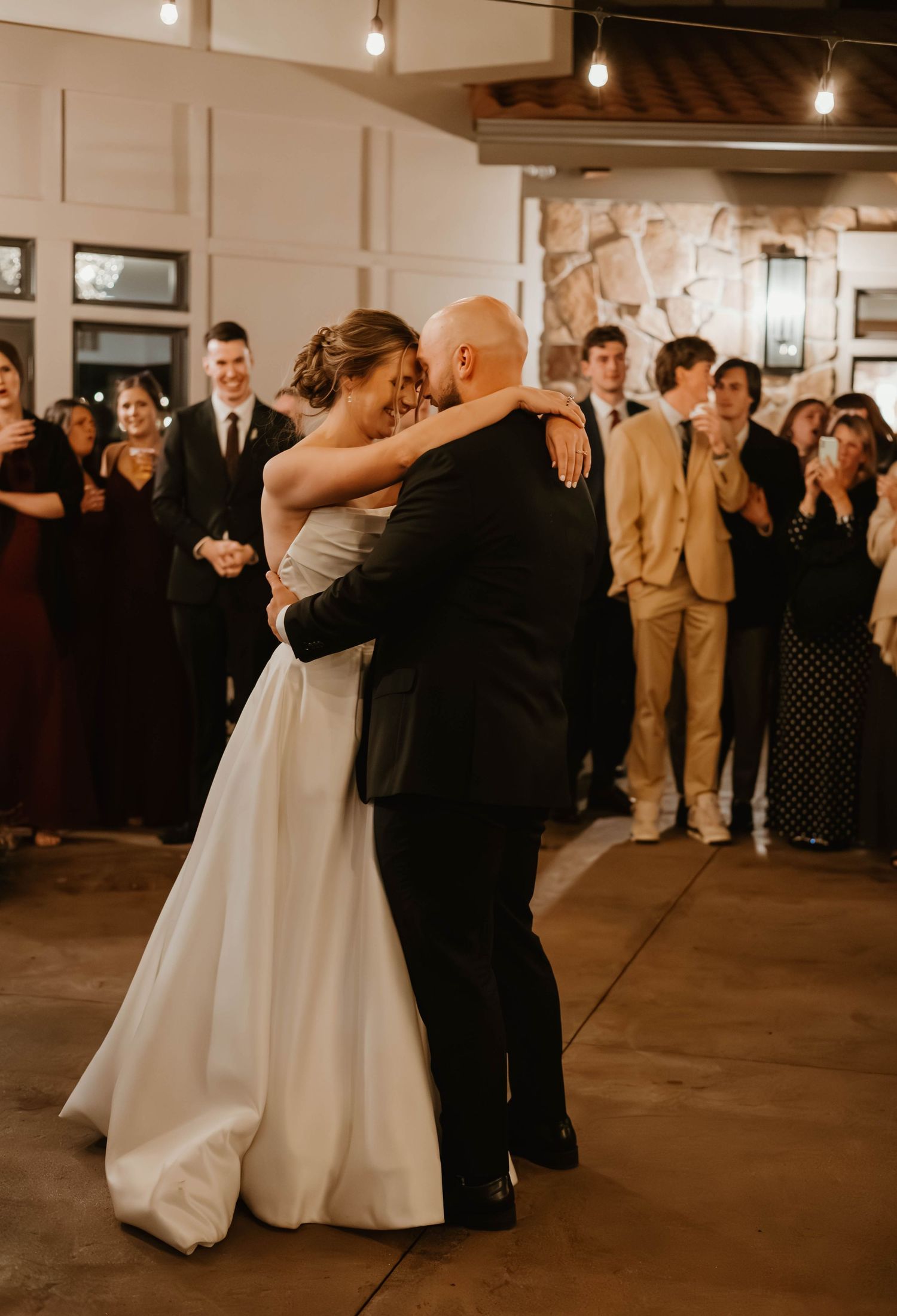 Wedding guests watch as couple shares their first dance in an industrial-style reception space.