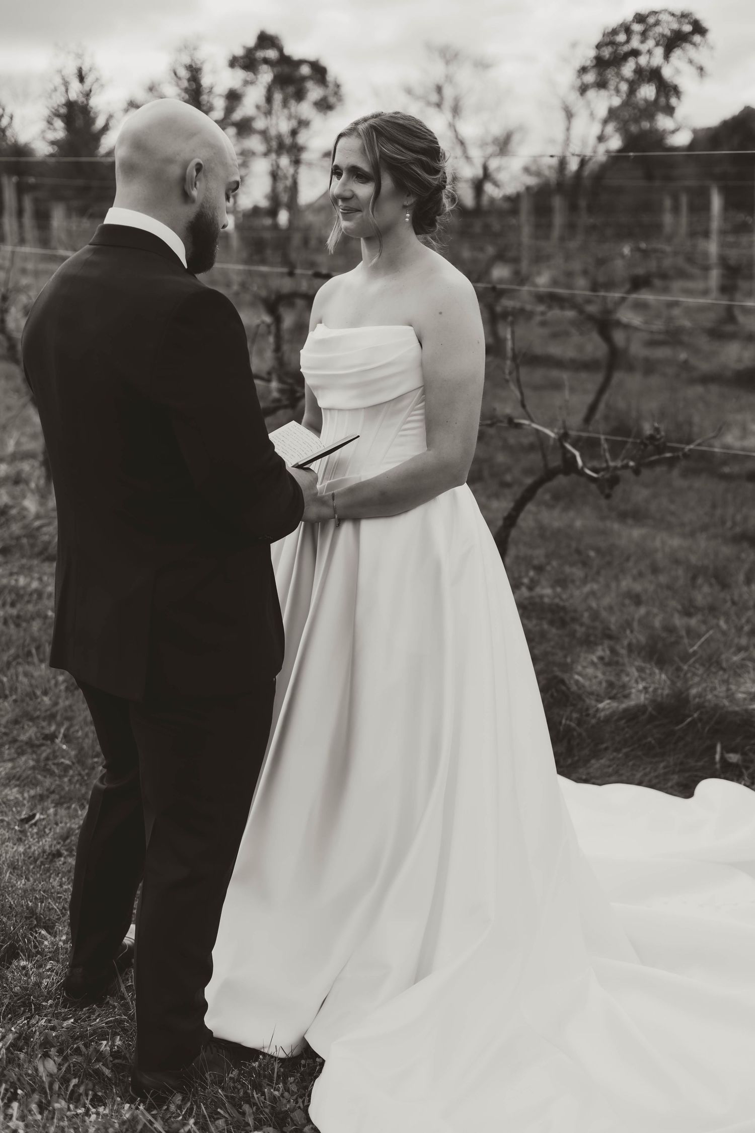 An intimate wedding ceremony moment in a rustic vineyard setting.