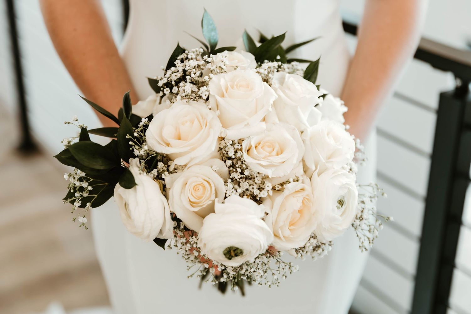 Close-up of cream roses and baby's breath bouquet against white fabric.