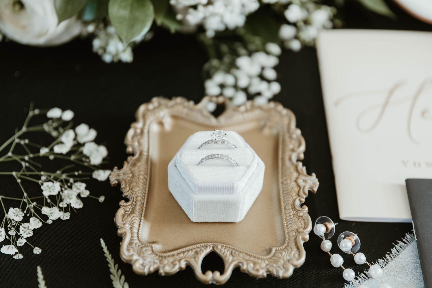 Elegant wedding place cards with baby's breath flowers arranged on ornate gold frames against a dark background.