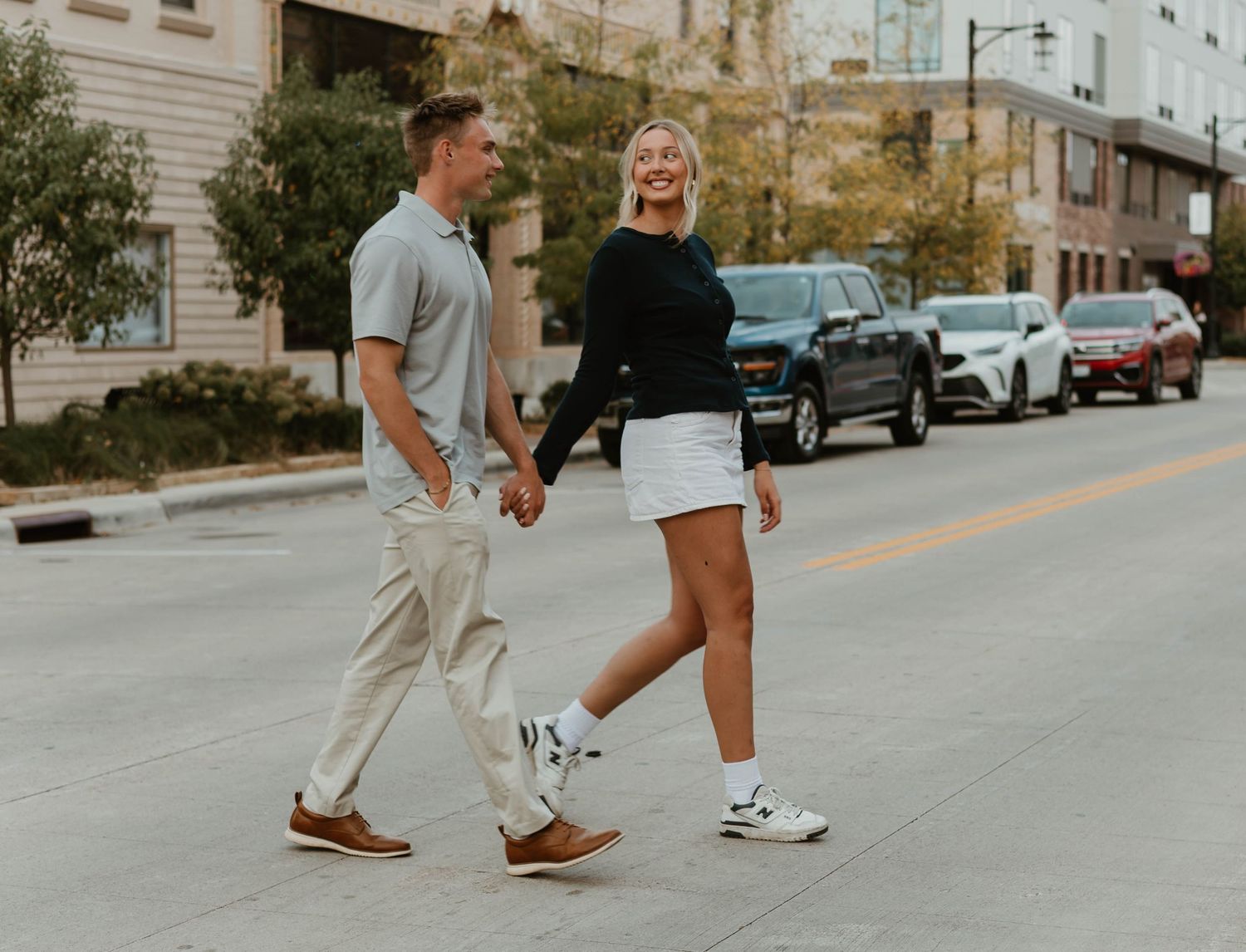 Two people walking together on a sidewalk in a casual urban setting on a sunny day.