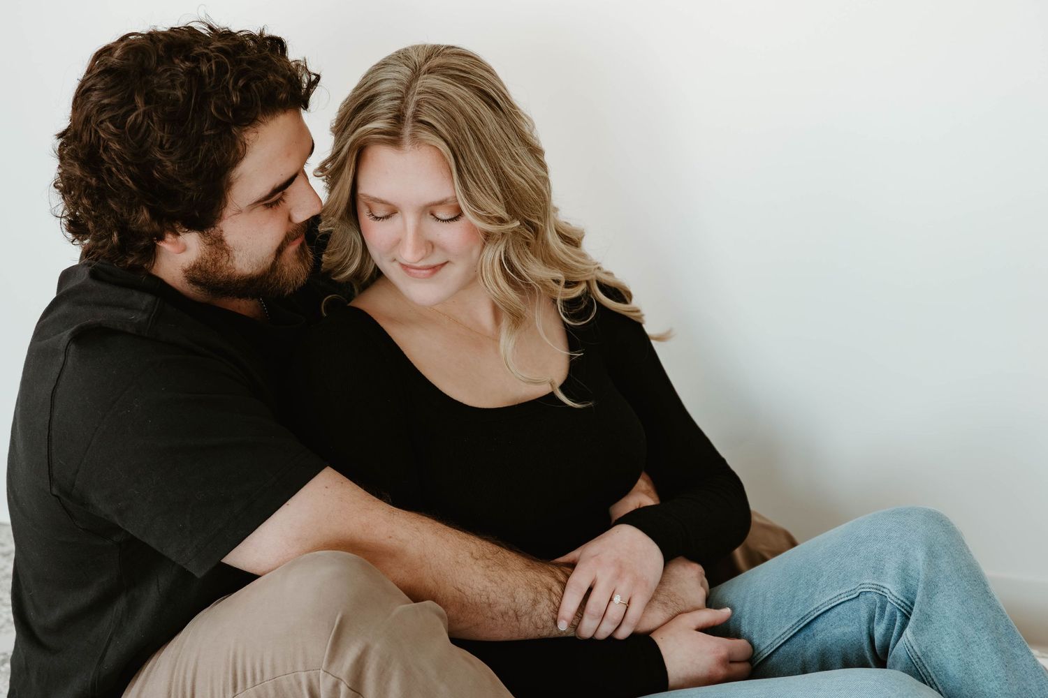 A couple in black clothing shares intimate moments in a series of romantic poses against a light background.