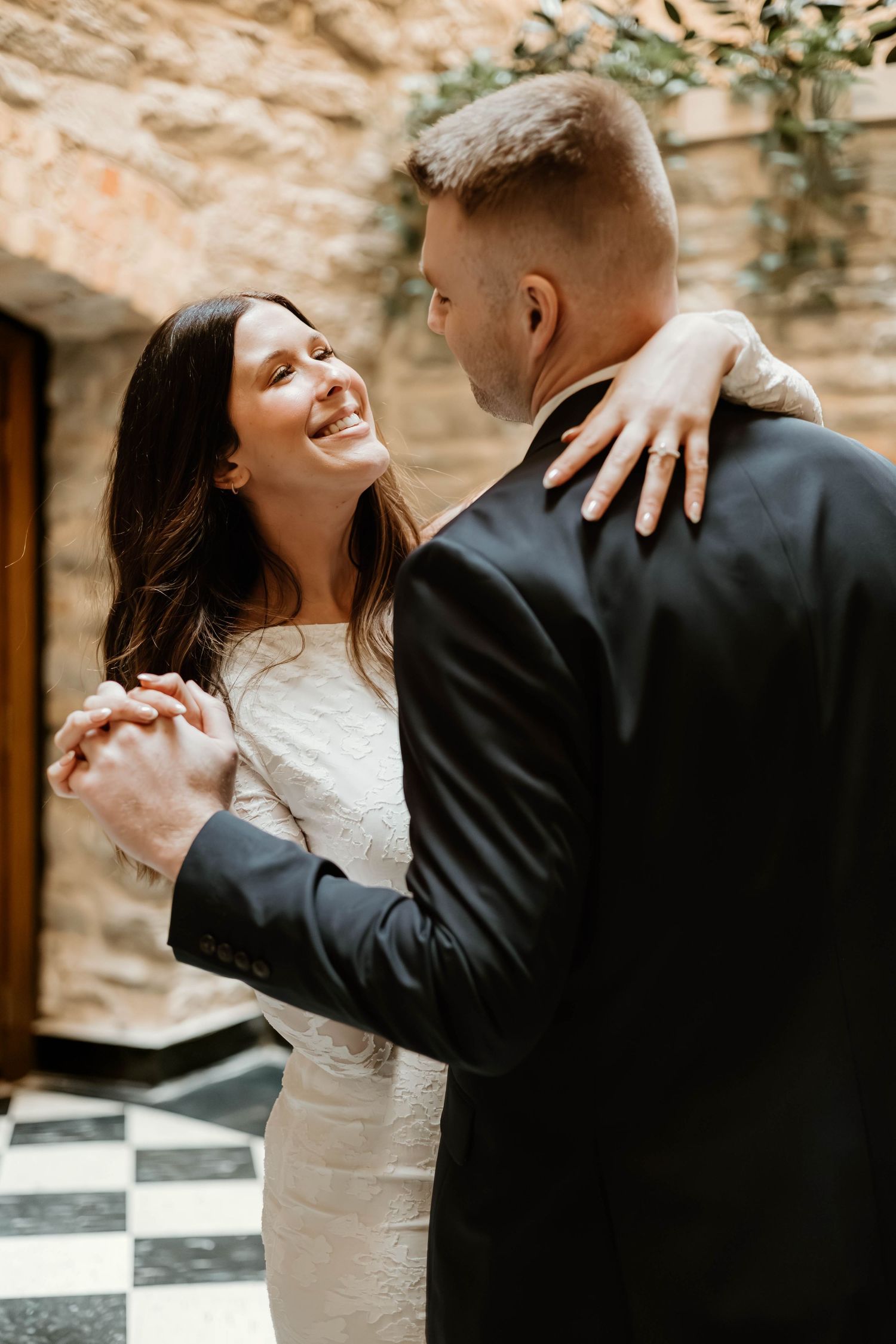 A couple dances together in formal wedding attire, creating a series of romantic movement shots against a stone backdrop.