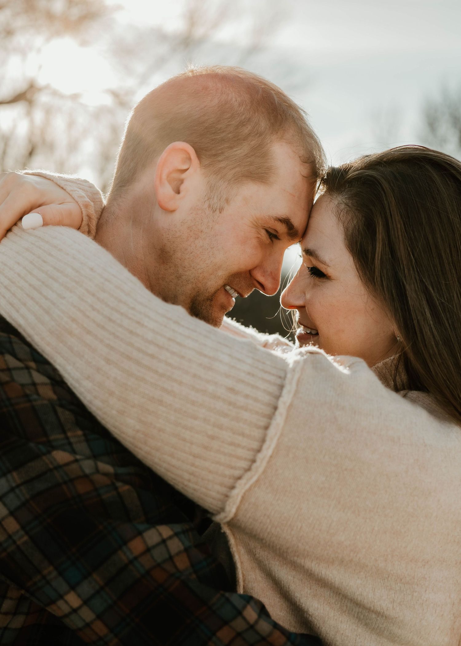 A couple shares an intimate moment in soft lighting while wearing cozy sweaters.