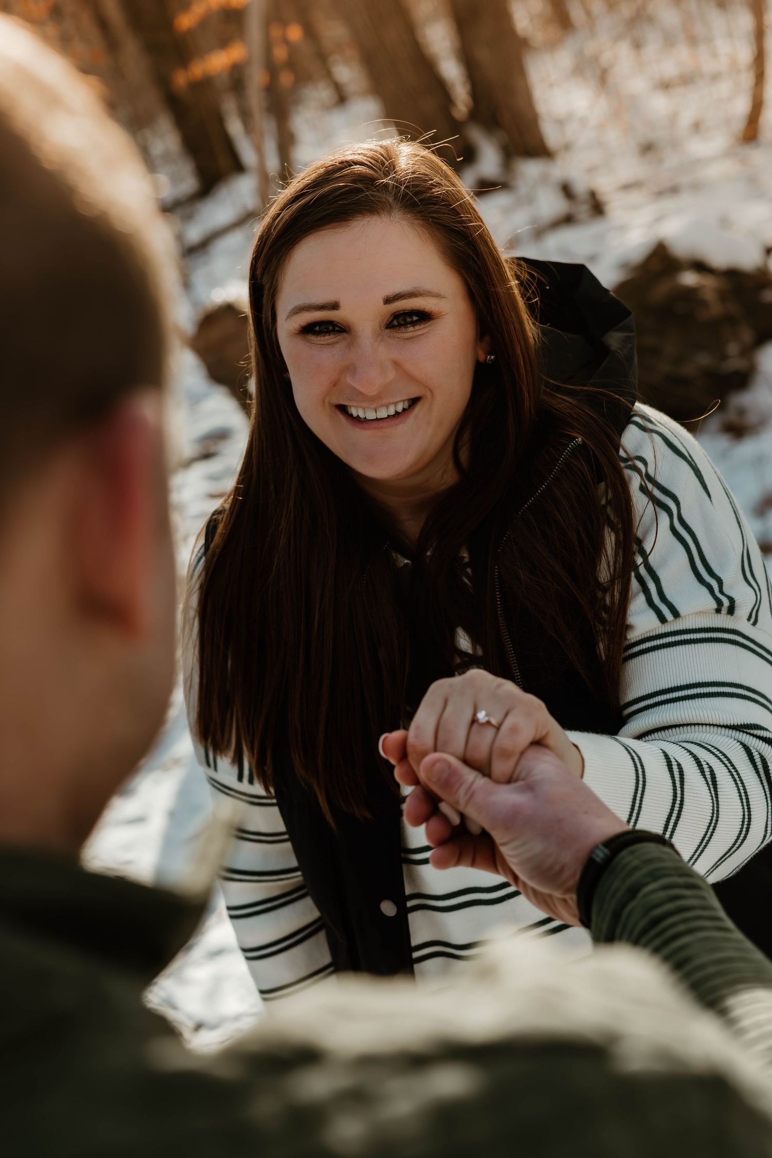 A joyful moment captured between two people during a winter engagement photoshoot in the woods.