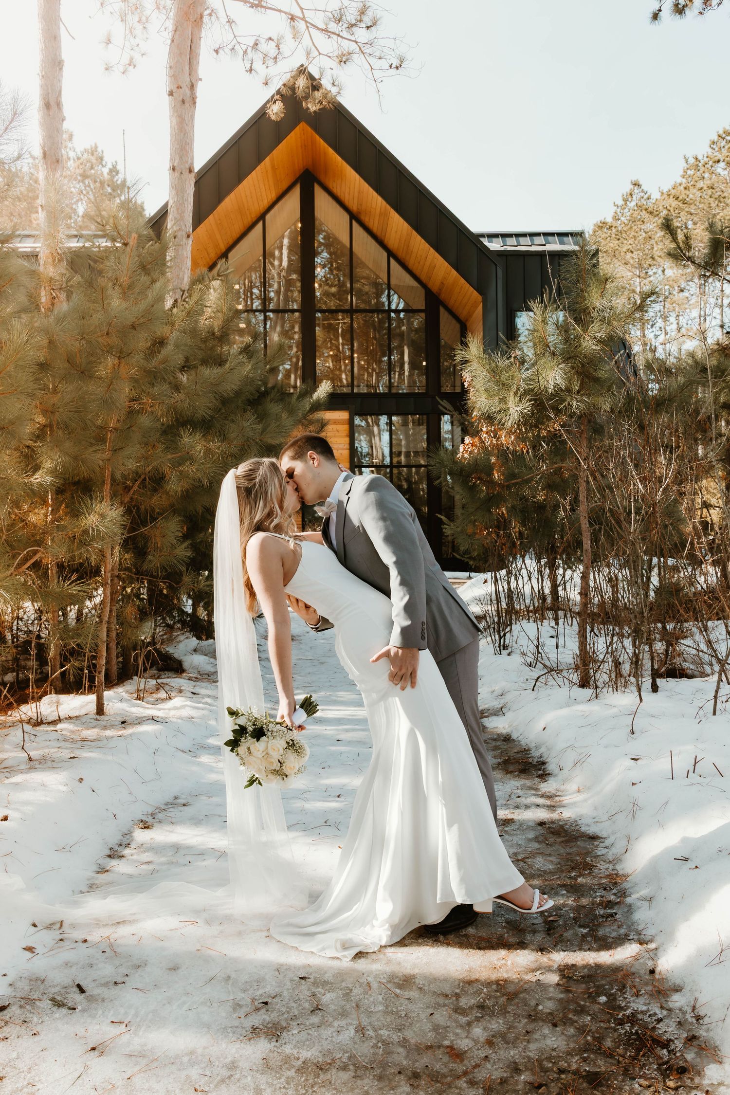 Winter wedding photo series with snowy landscape and A-frame chapel in warm sunset lighting.