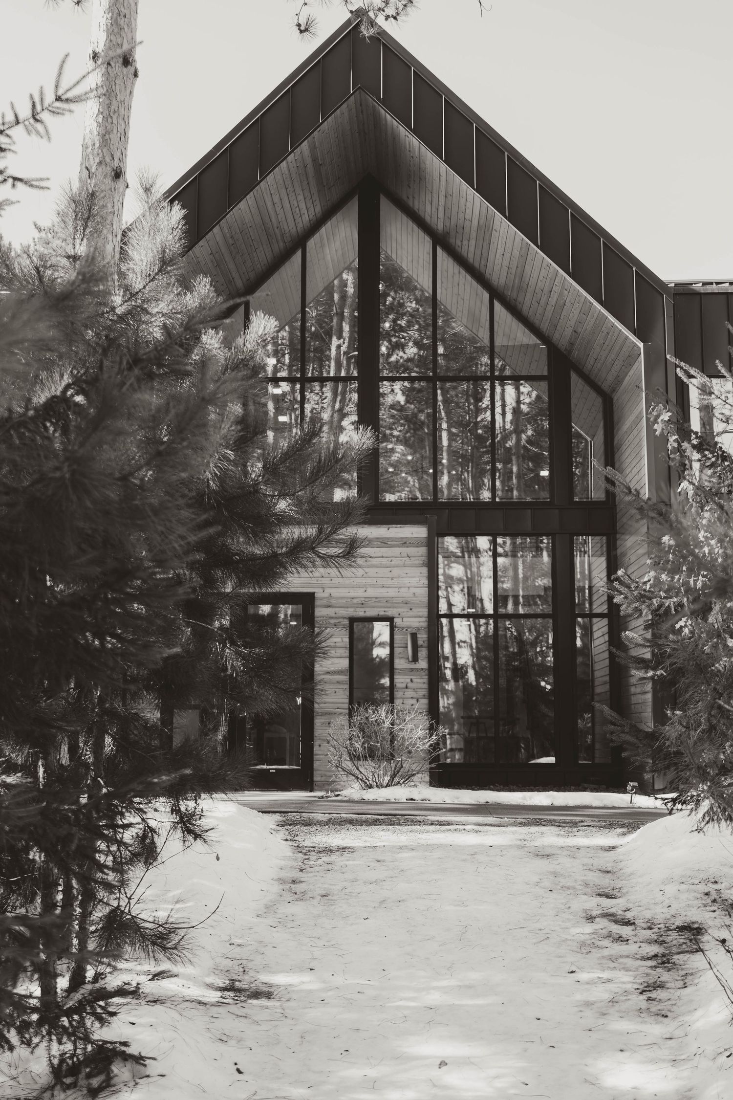 Modern A-frame chapel in a snowy forest setting with large glass windows and stone accents.