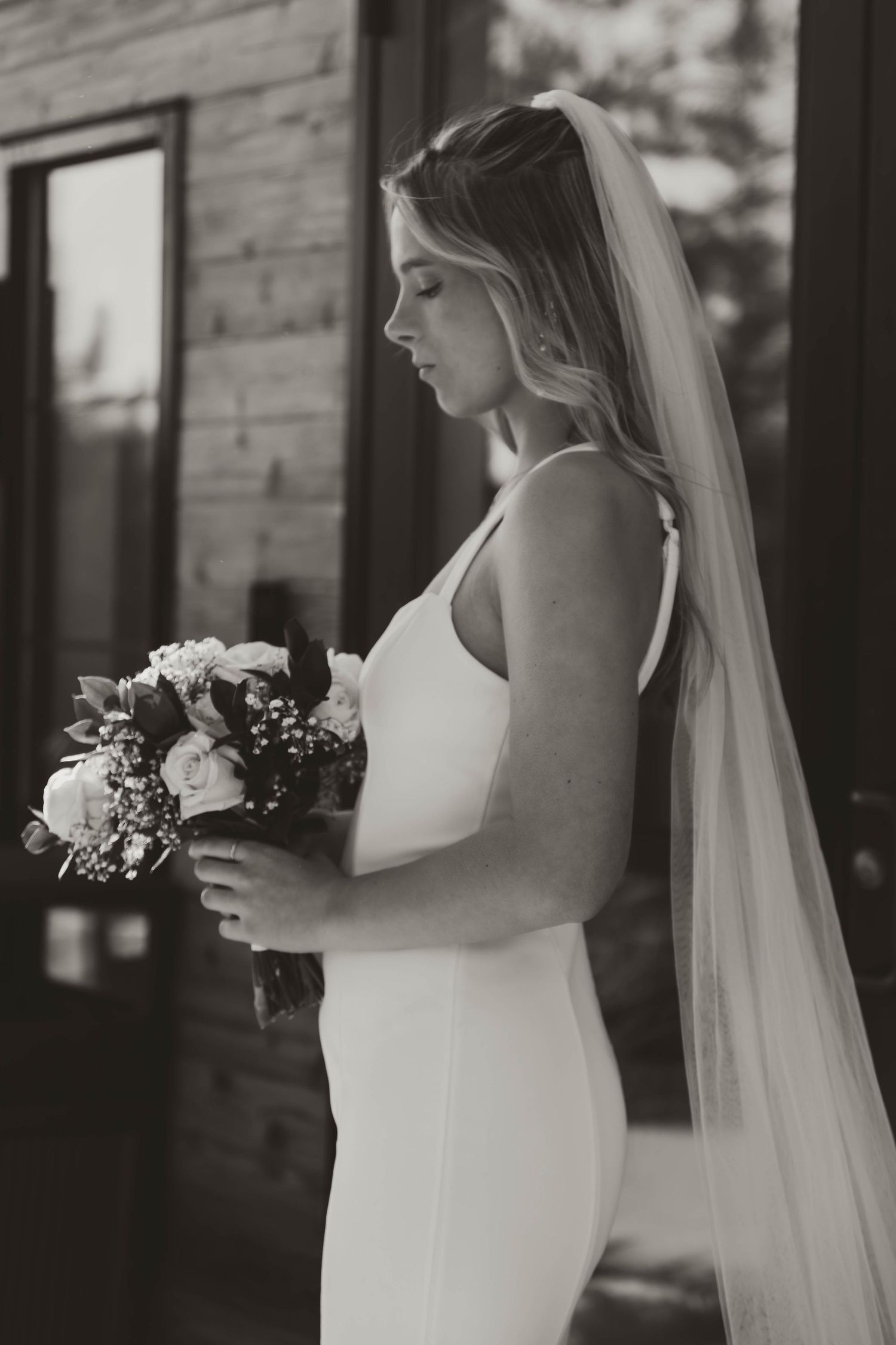 Black and white portraits of bride holding bouquet in elegant white dress with flowing veil.