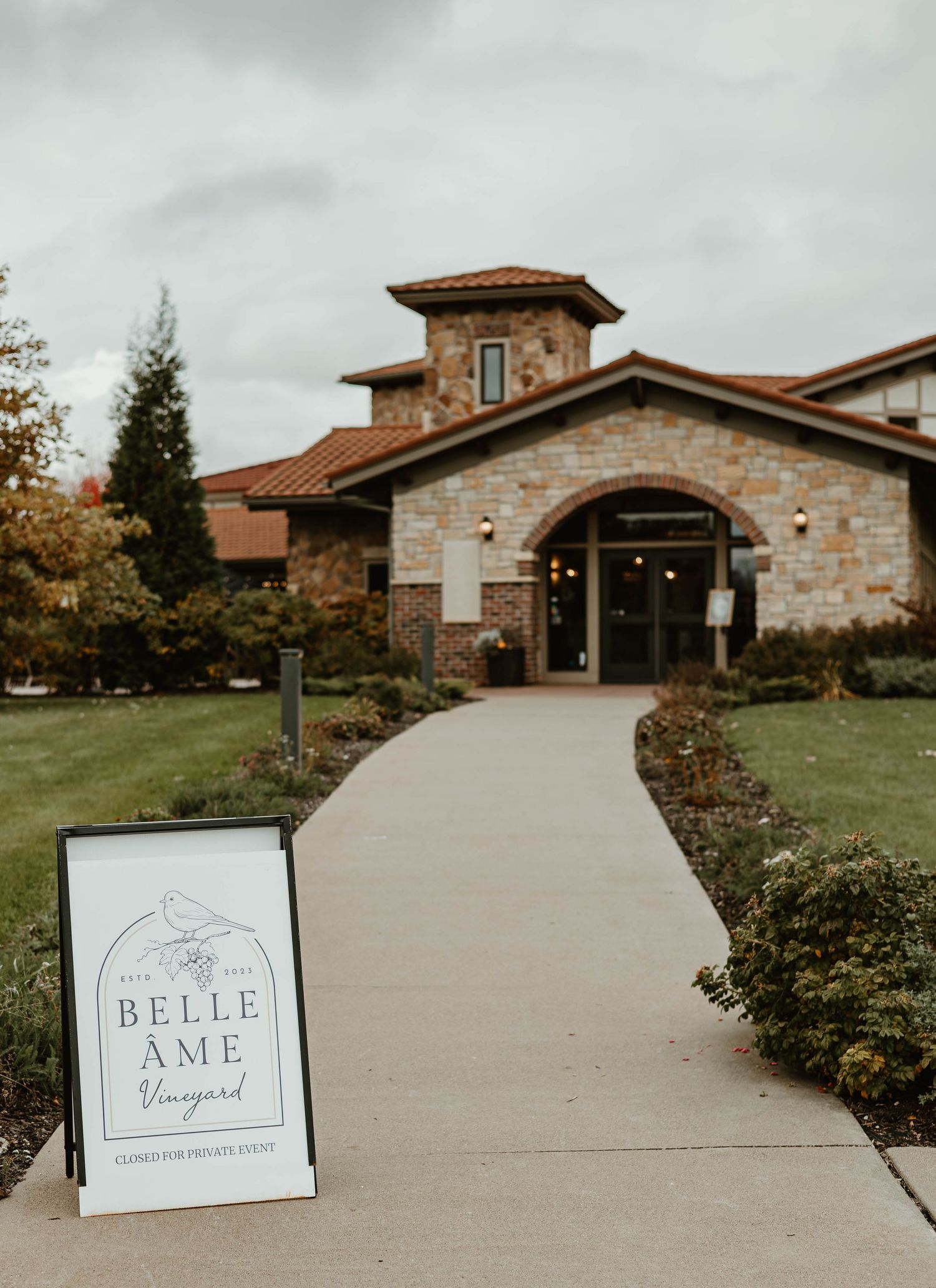 Entrance to Belle Vineyard with stone facade and concrete pathway leading to modern winery building.