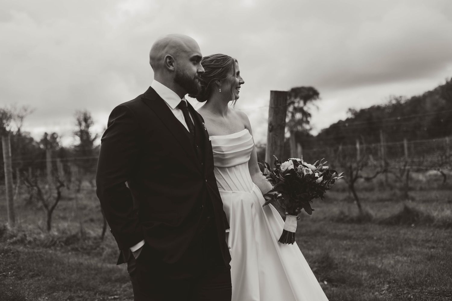 A couple shares intimate moments during their wedding photoshoot in a rustic vineyard setting.