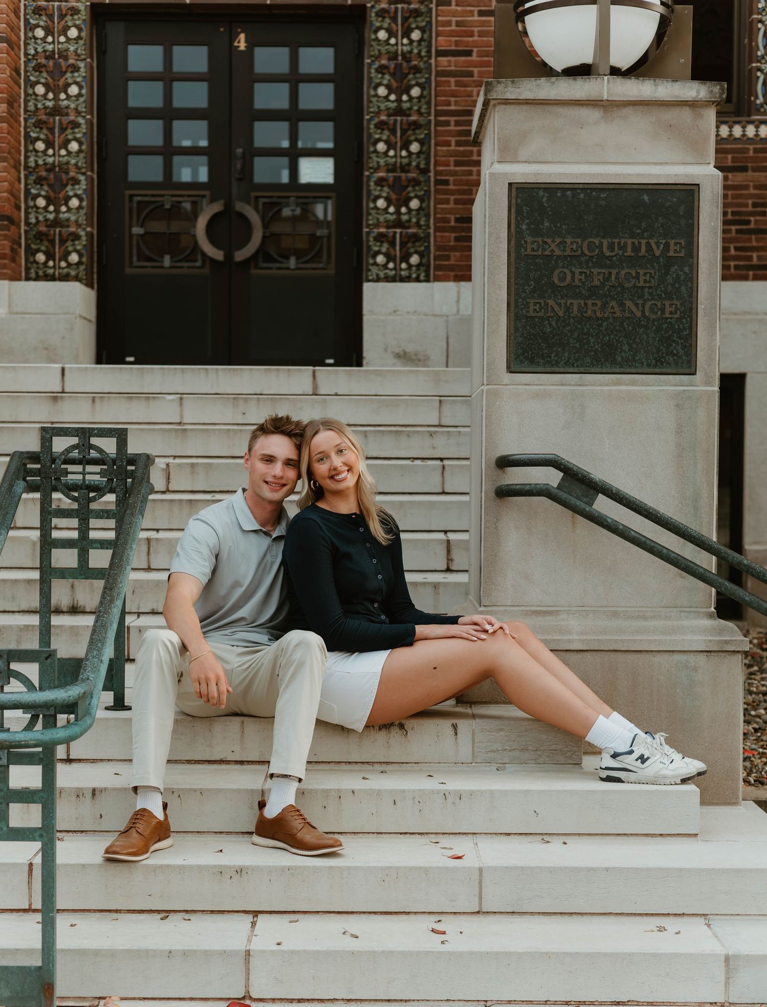 Romantic moment captured on architectural stone steps with brick building backdrop.