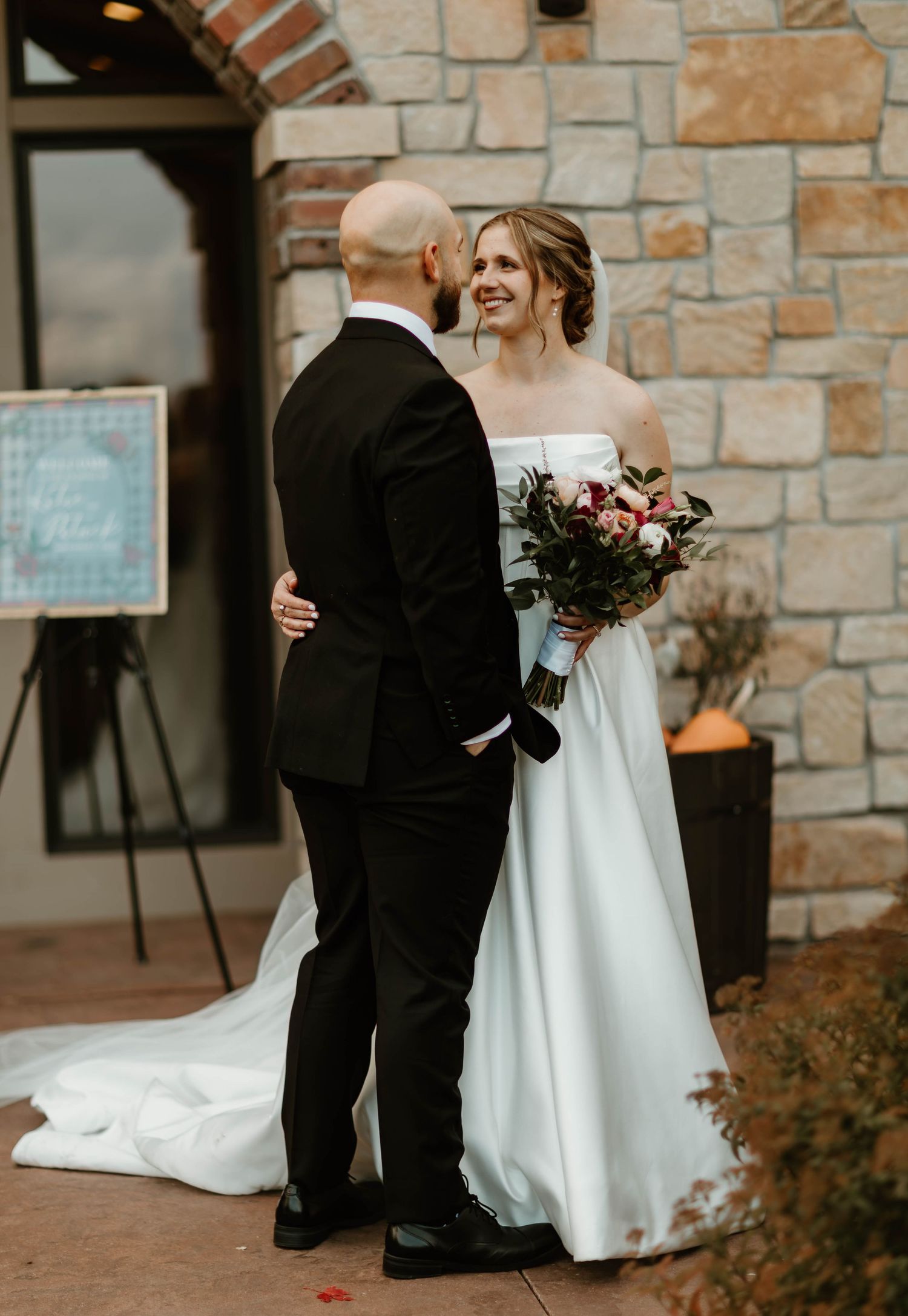 Couple sharing tender moments against a stone wall backdrop during their wedding.