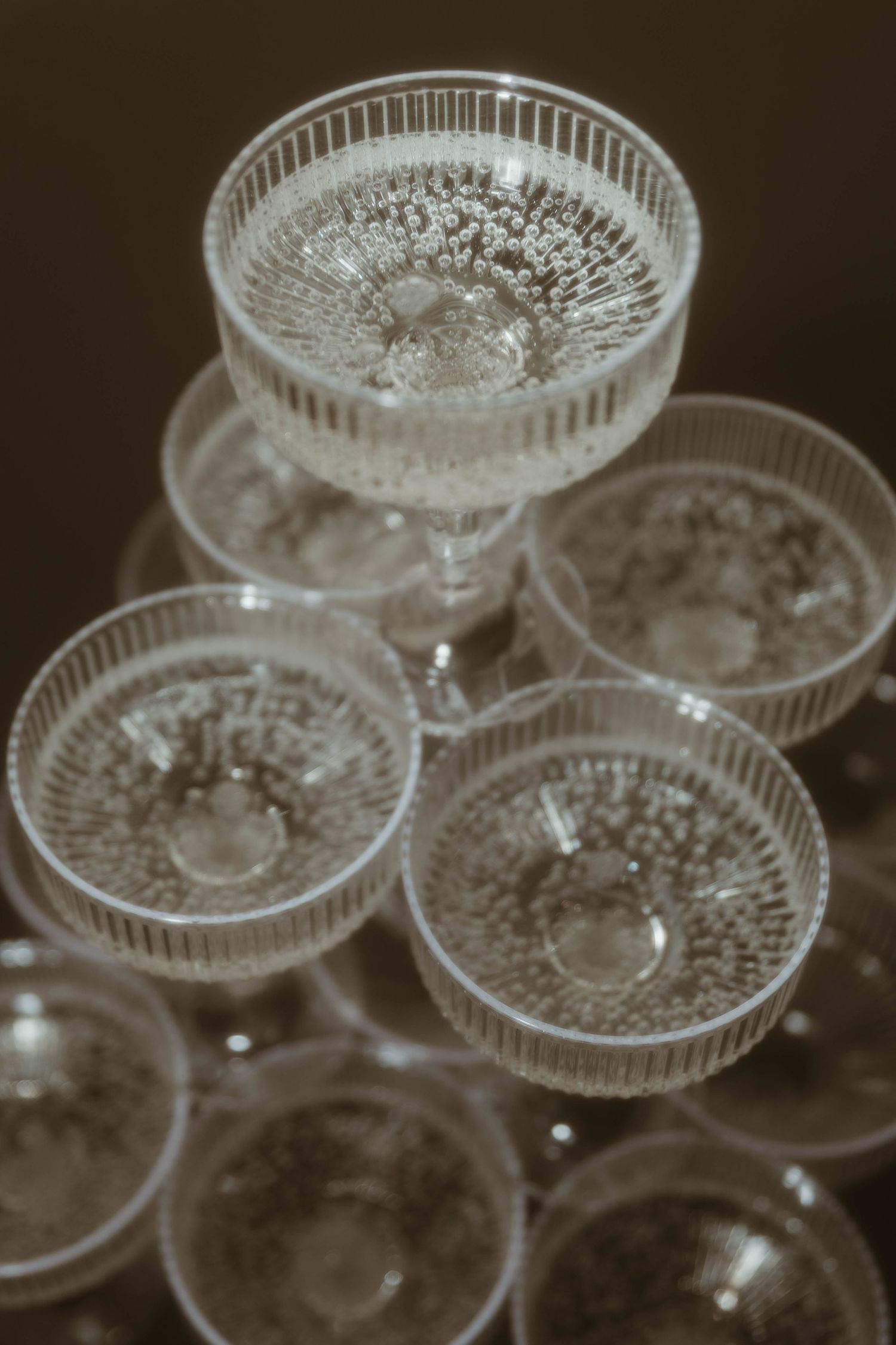 Vintage crystal champagne coupes stacked in a pyramid formation for a wedding celebration.