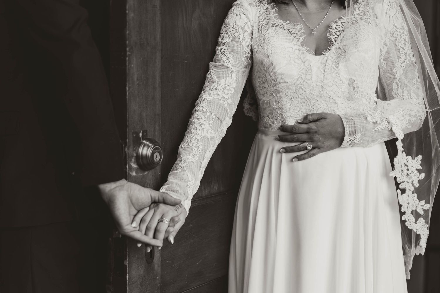 Close-up detail of long-sleeved lace wedding dress and bouquet.