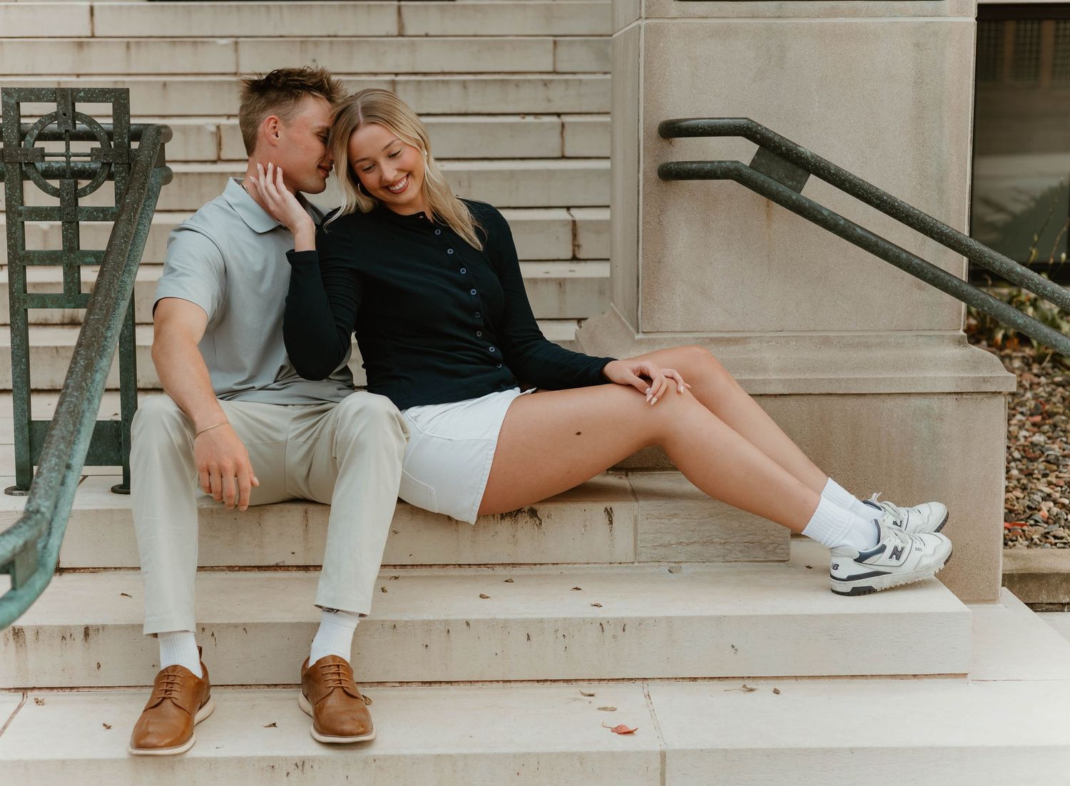 Candid moments between couple relaxing on concrete steps outside historic building.