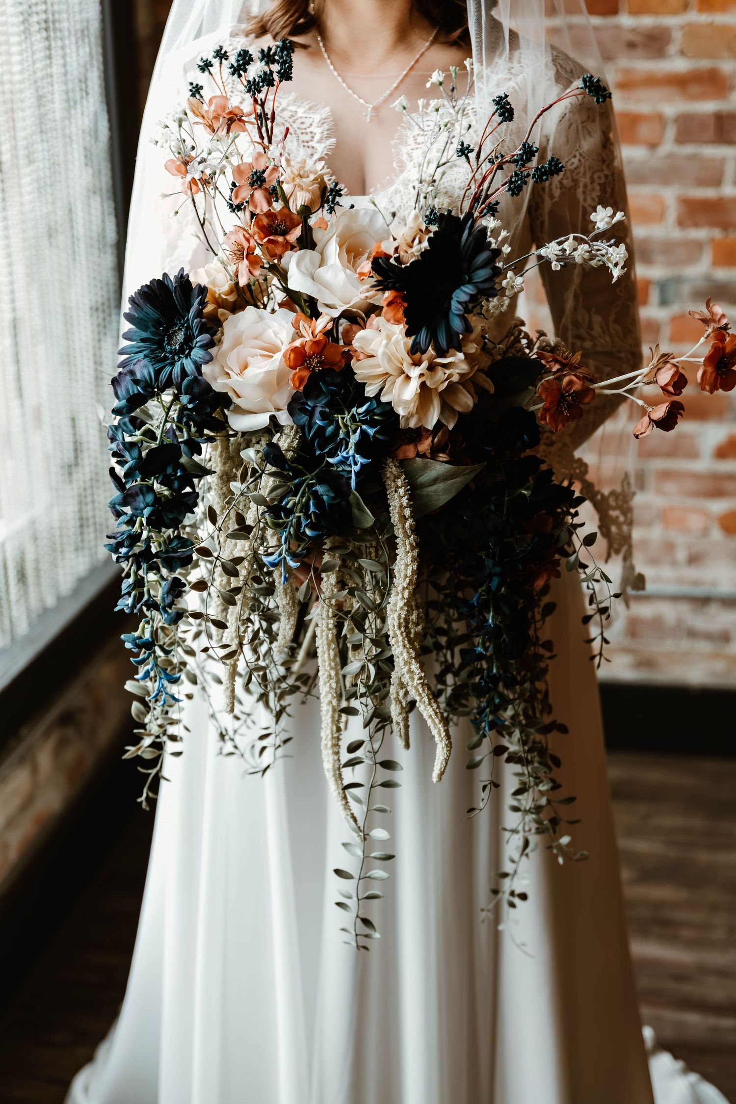 Stunning bridal bouquet with navy blue and peach flowers against a white wedding dress.