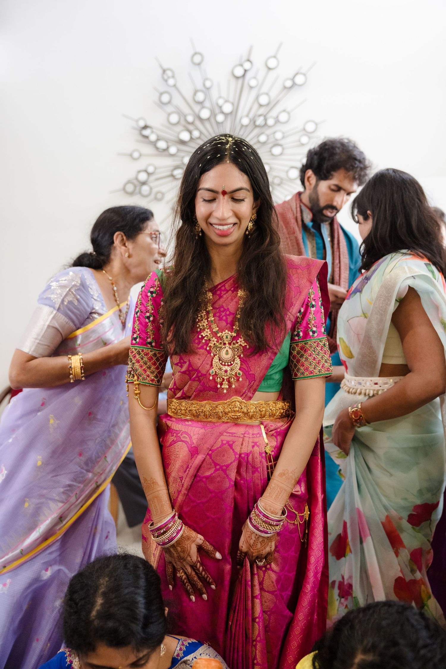 Guests in colorful traditional Indian attire celebrate at a festive gathering with vibrant saris and gold jewelry.