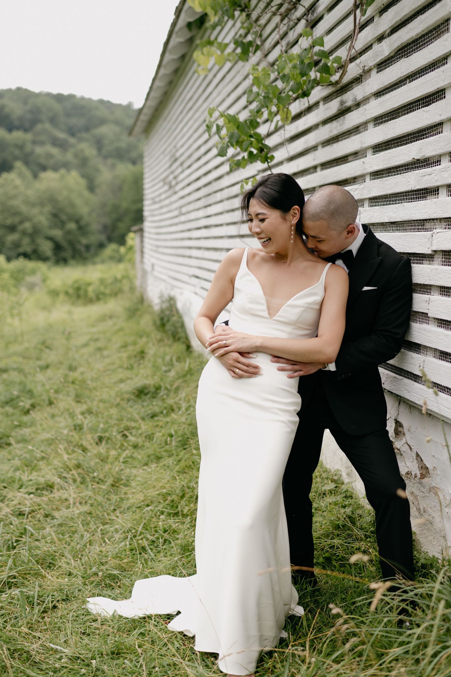 Romantic couple portrait against white slatted wall in outdoor setting.