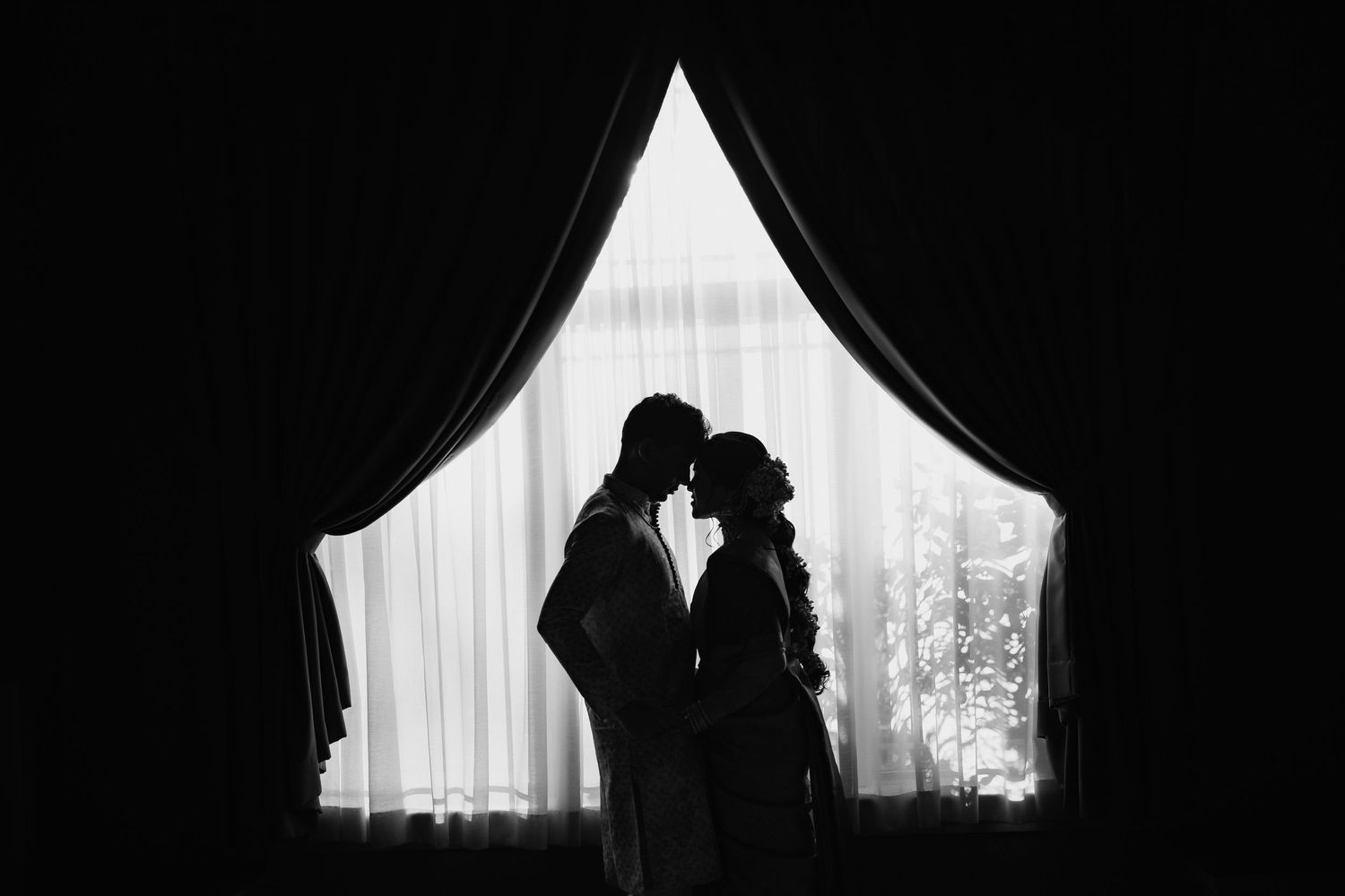 Silhouetted figures in dramatic black and white window lighting.