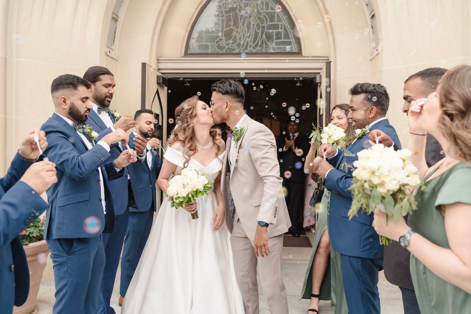Wedding celebration outside church with guests throwing confetti at newlyweds.