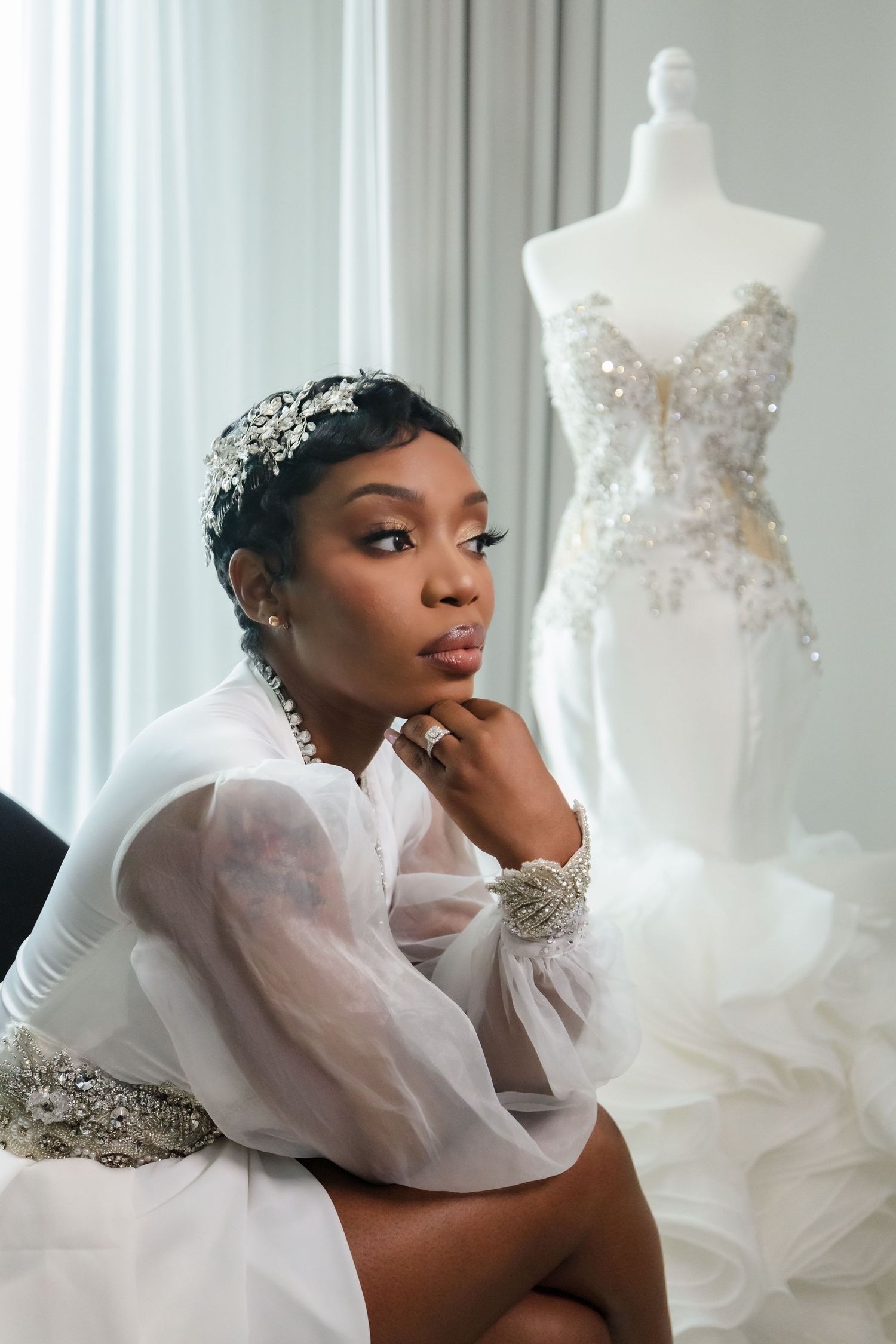 Elegant bridal portrait session featuring white wedding dresses displayed against soft curtained backdrop.