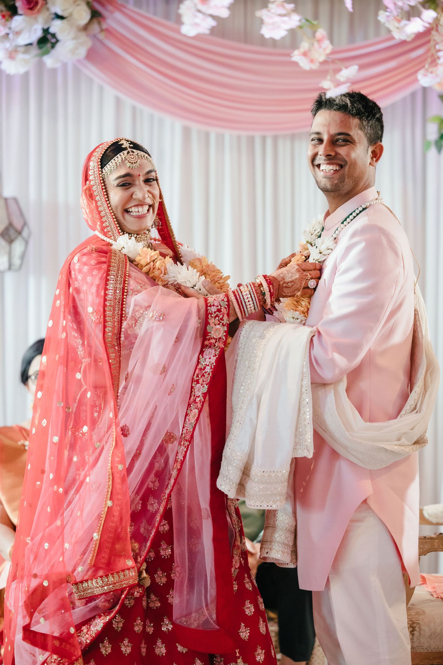 Wedding celebration in pink and white decorated venue with traditional attire.