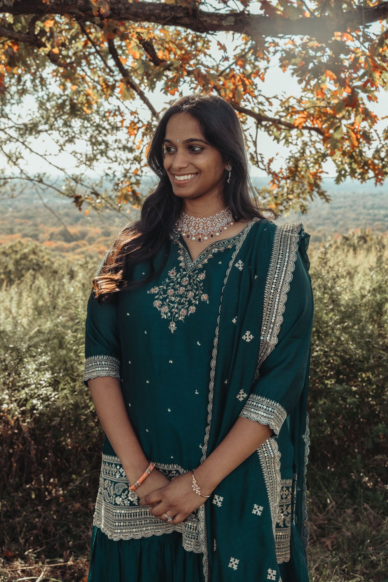 Emerald green traditional outfit with silver embroidery photographed in golden sunlight.