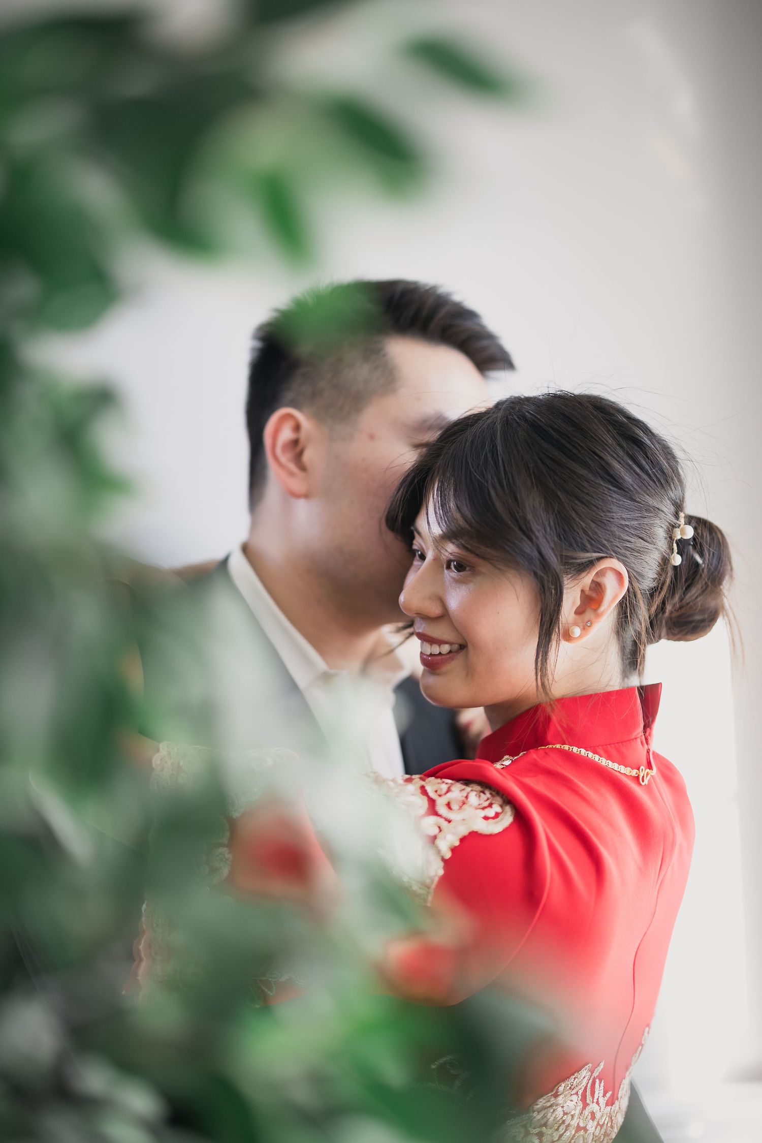 Traditional Chinese tea ceremony with couple in red attire surrounded by greenery.