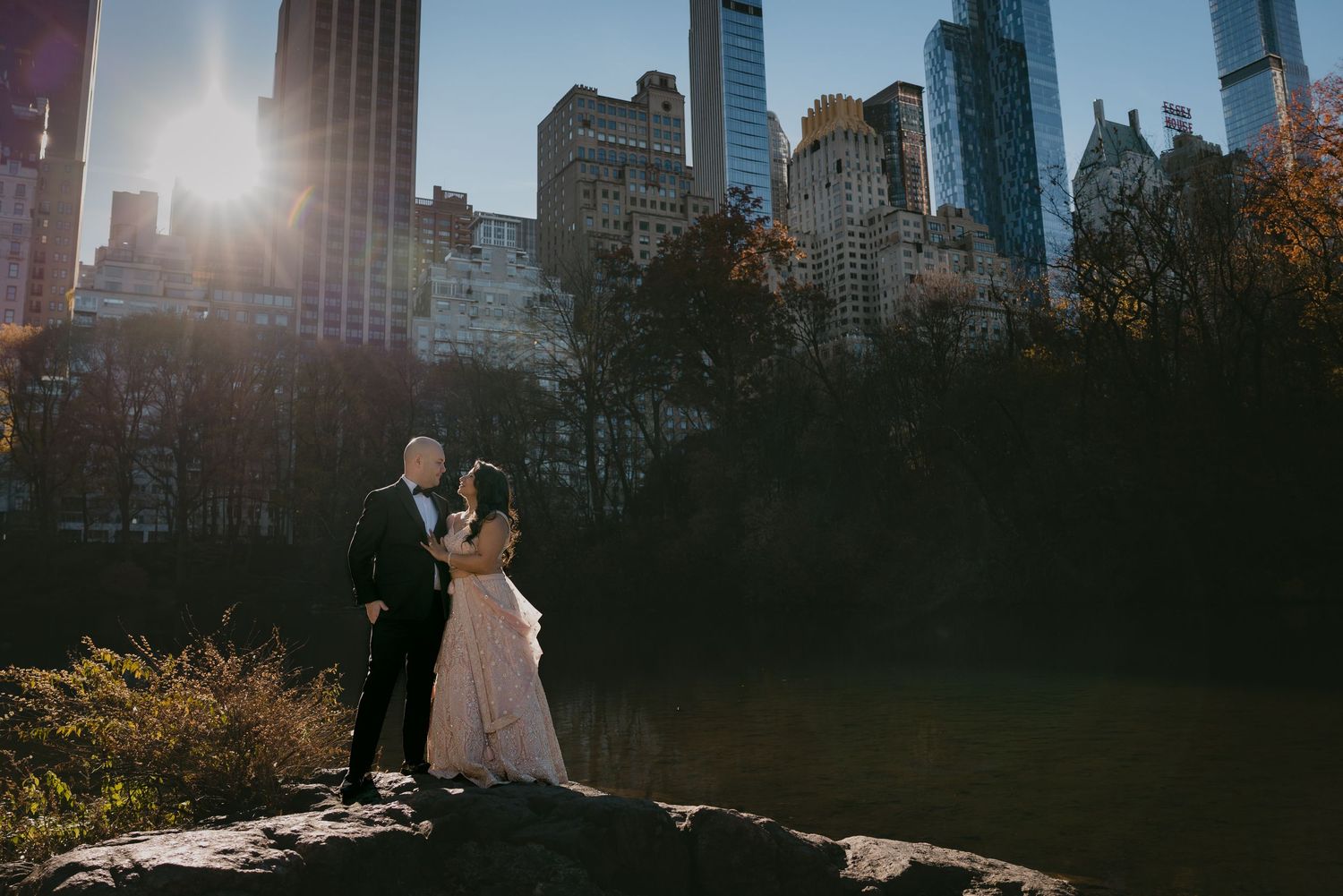 Scenic wedding photo with Manhattan skyline and golden sunset light.