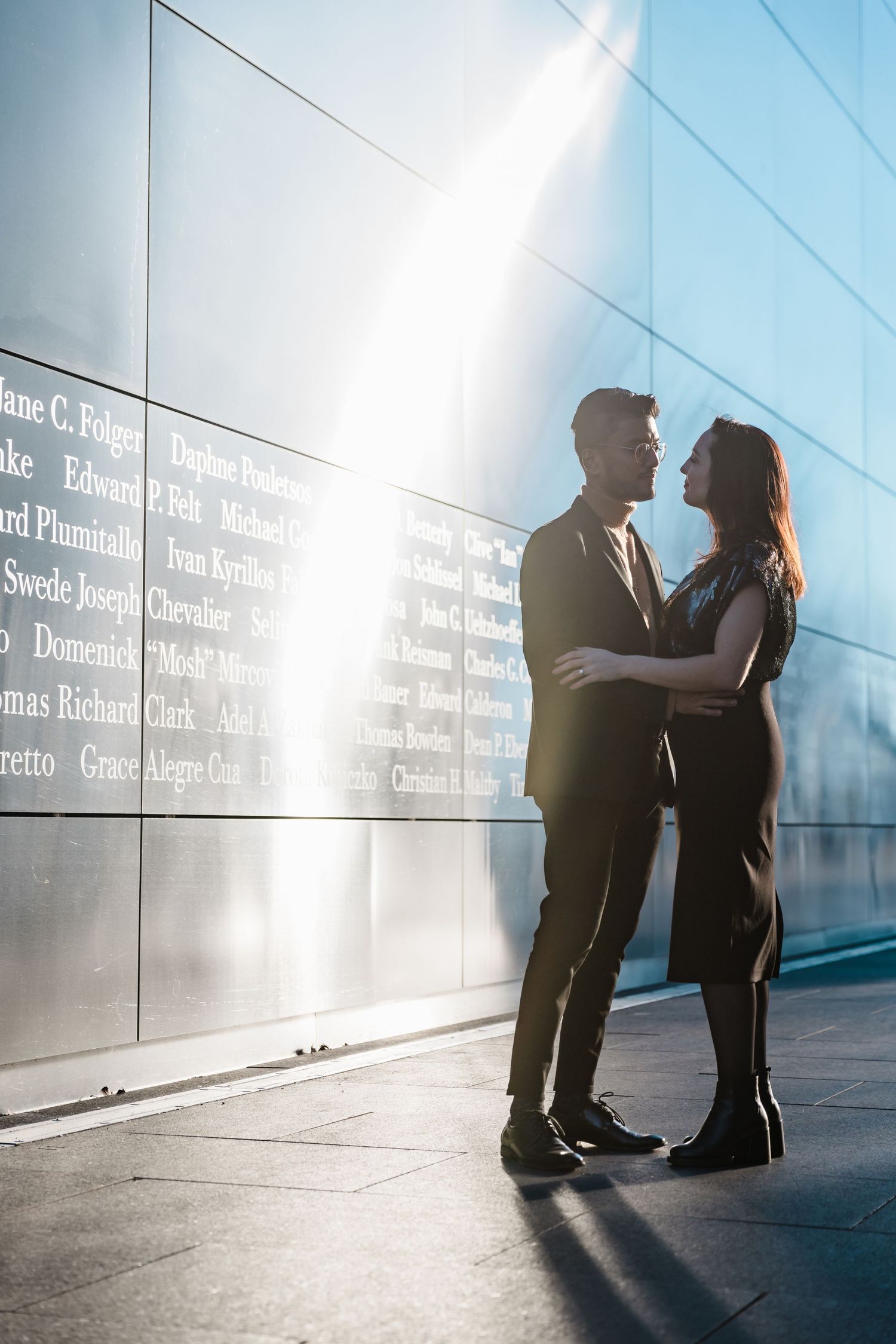 Silhouettes of a couple against a modern wall with text in dramatic sunlight.