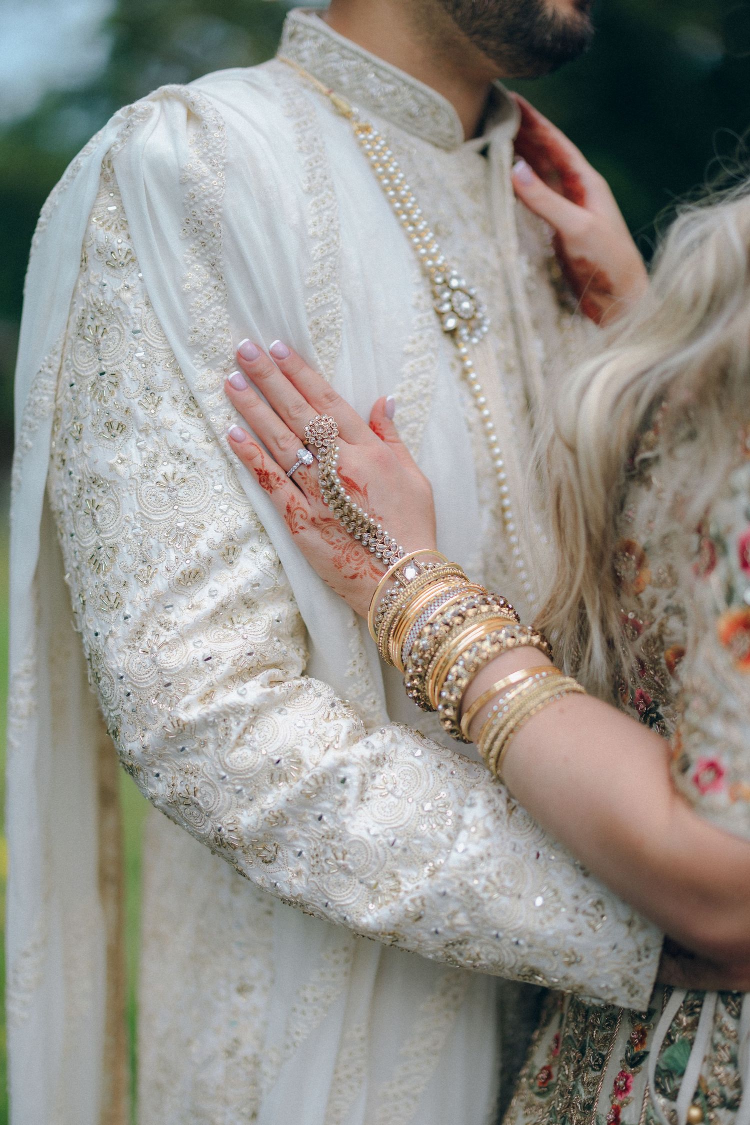 Close-up details of intricate bridal jewelry and embellished white sleeves.