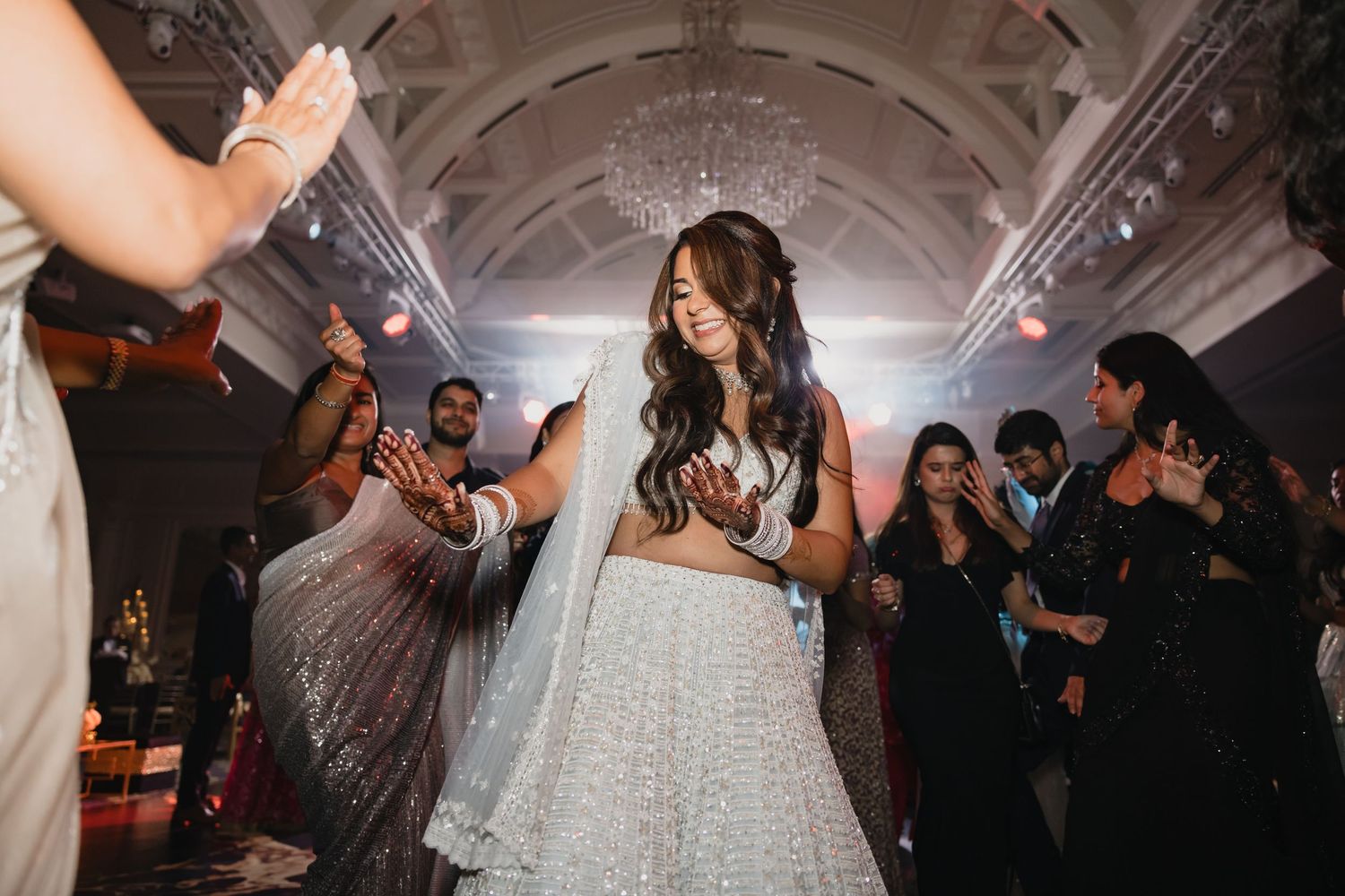 Wedding reception dance floor with guests celebrating under dramatic lighting and fog effects.