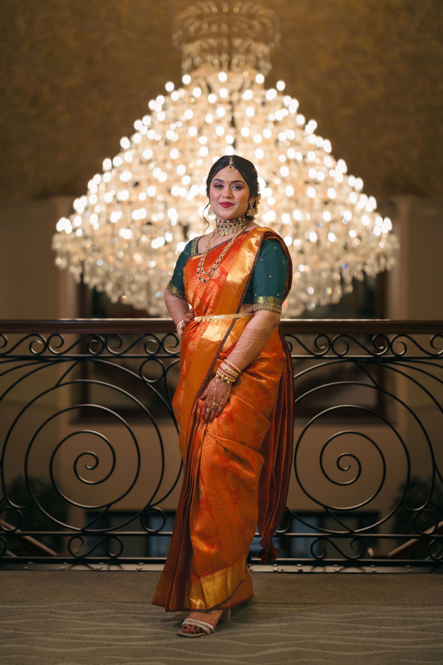 Traditional Indian attire showcased against elegant chandelier backdrop in formal setting.