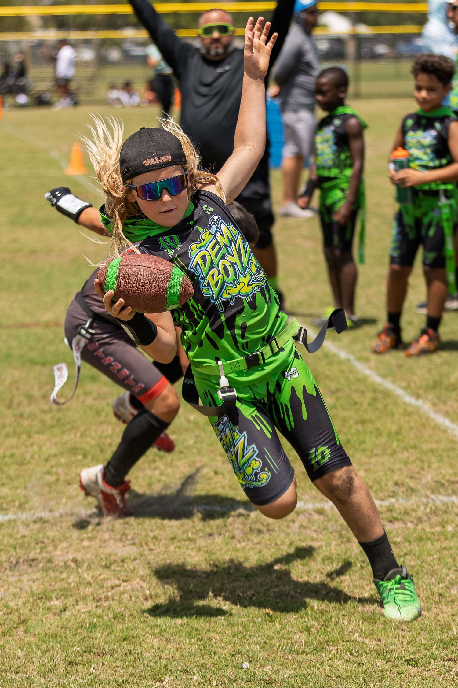 Youth football players diving for the ball in neon green uniforms during an intense game play.
