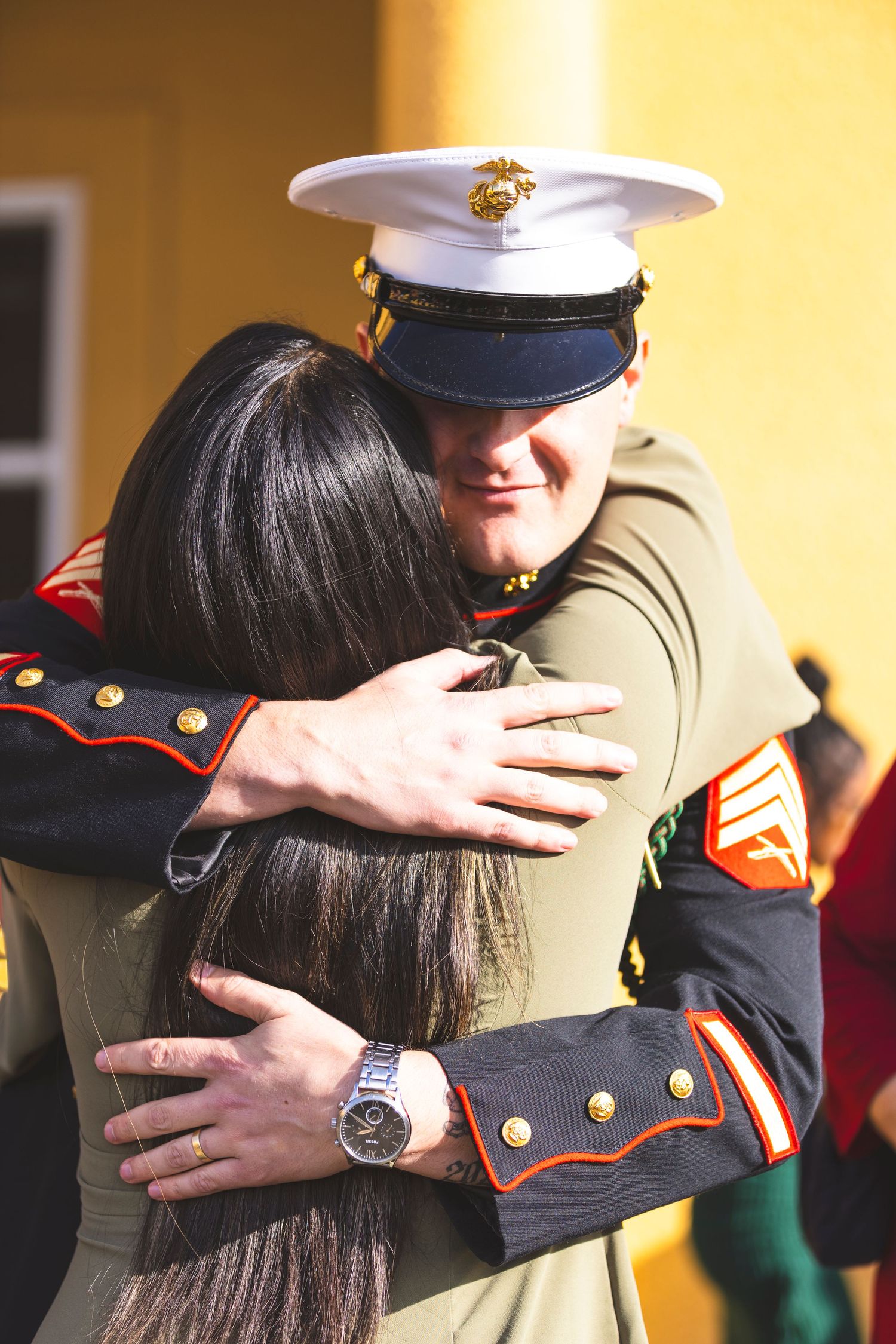 Marines in dress uniforms share emotional embraces during a ceremony.