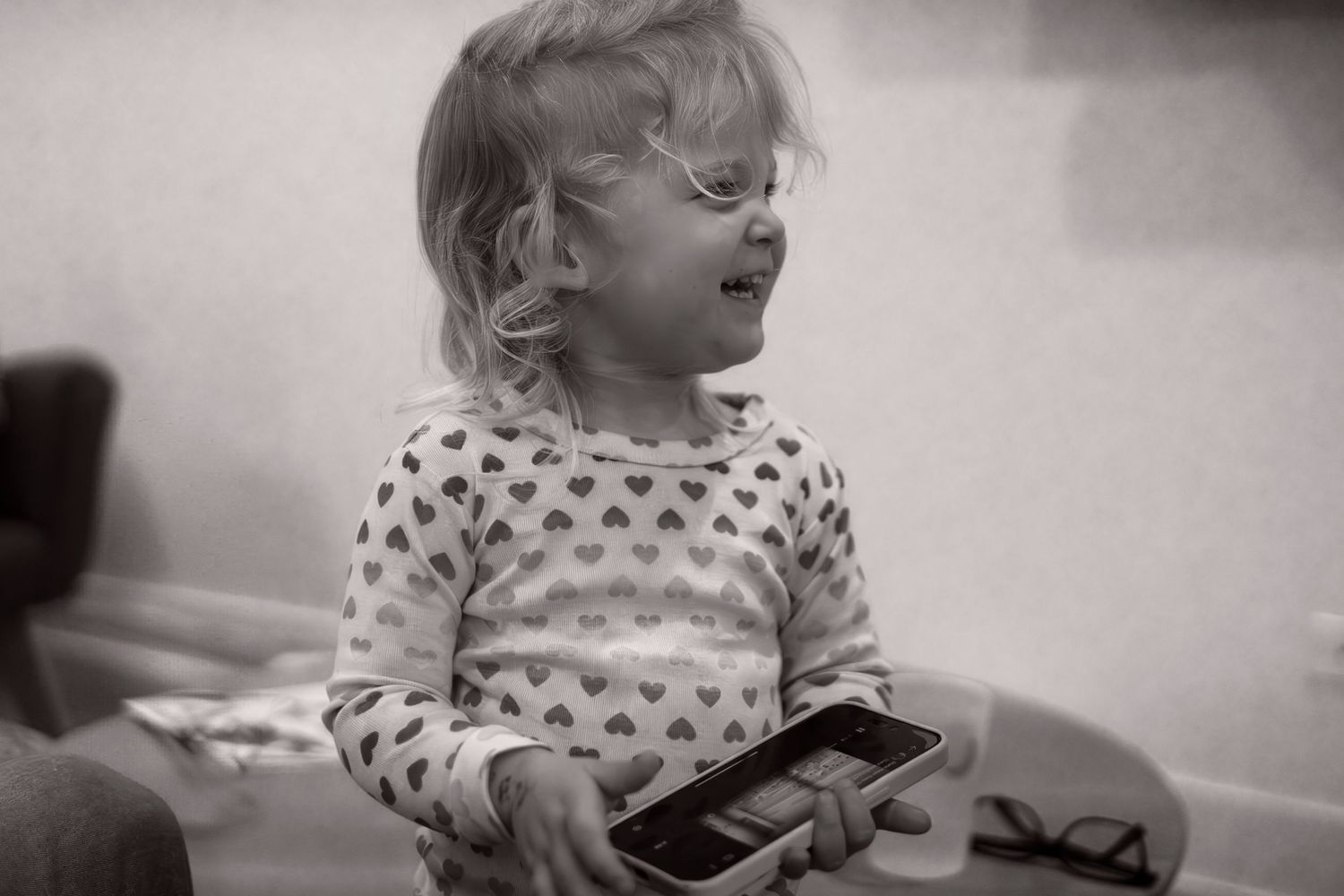 Child in heart patterned sweater laughing joyfully in black and white.